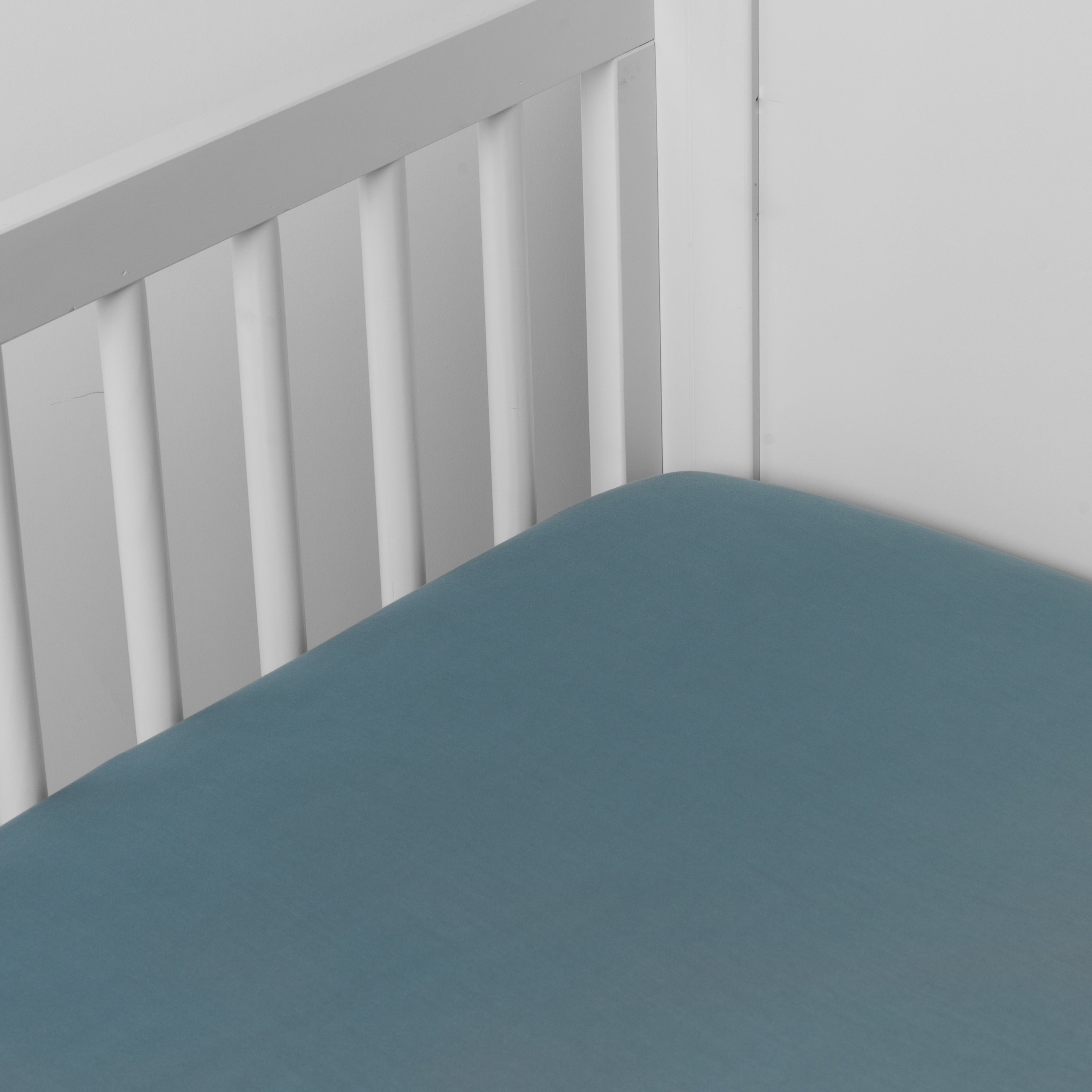 Cenote: crib sheet shown on a mattress shown from overhead into the corner of a crib.