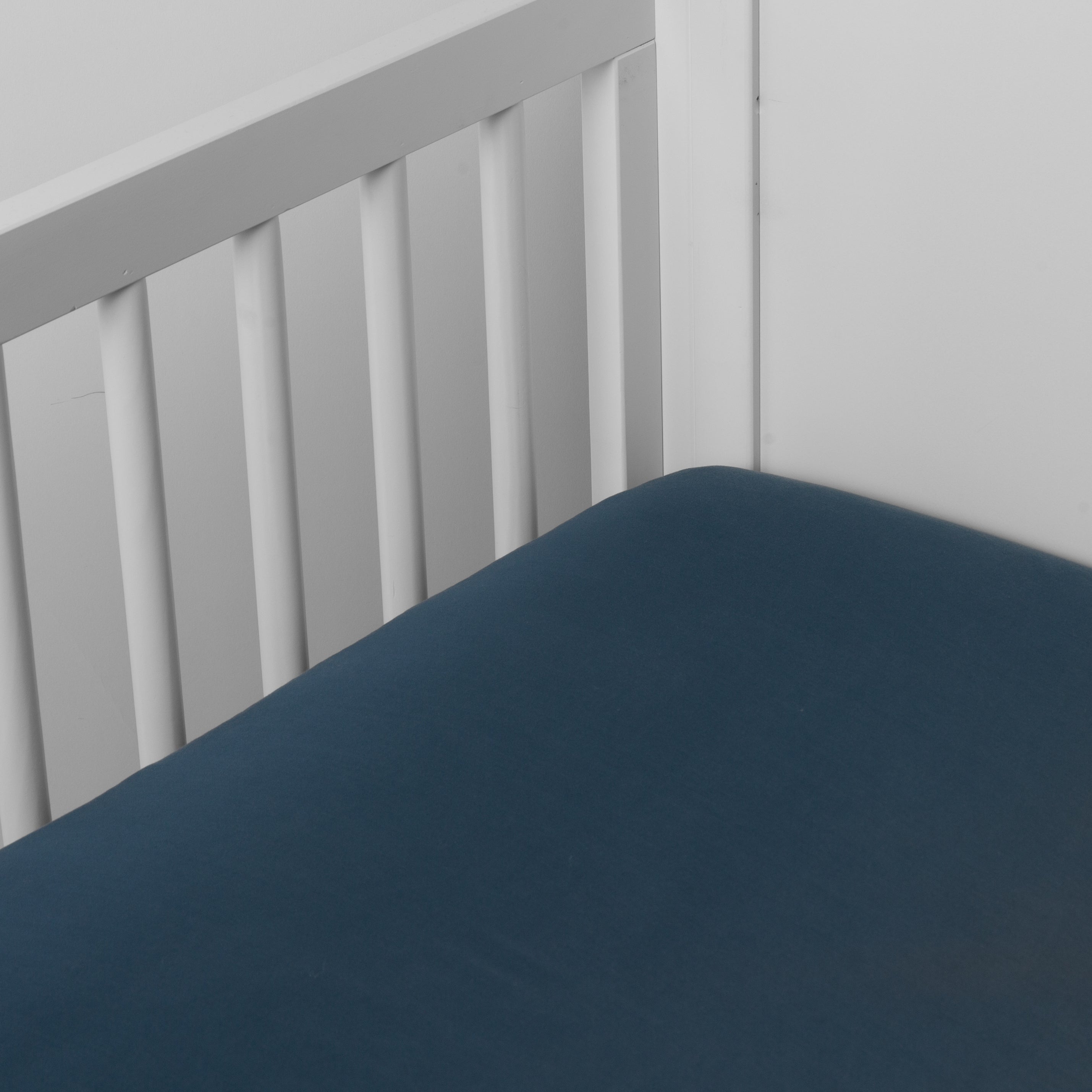 Midnight: crib sheet shown on a mattress shown from overhead into the corner of a crib.