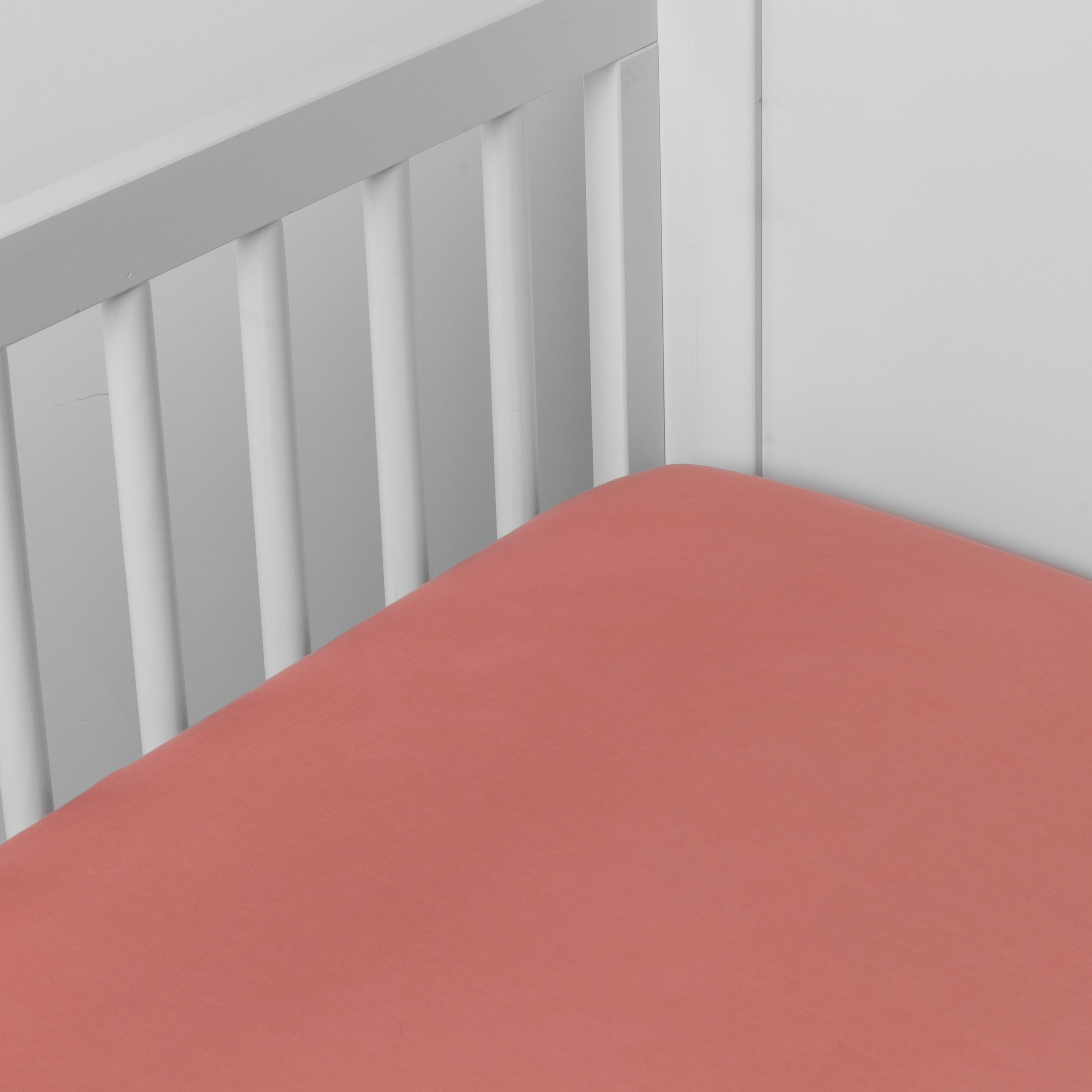 Poppy: crib sheet shown on a mattress shown from overhead into the corner of a crib.