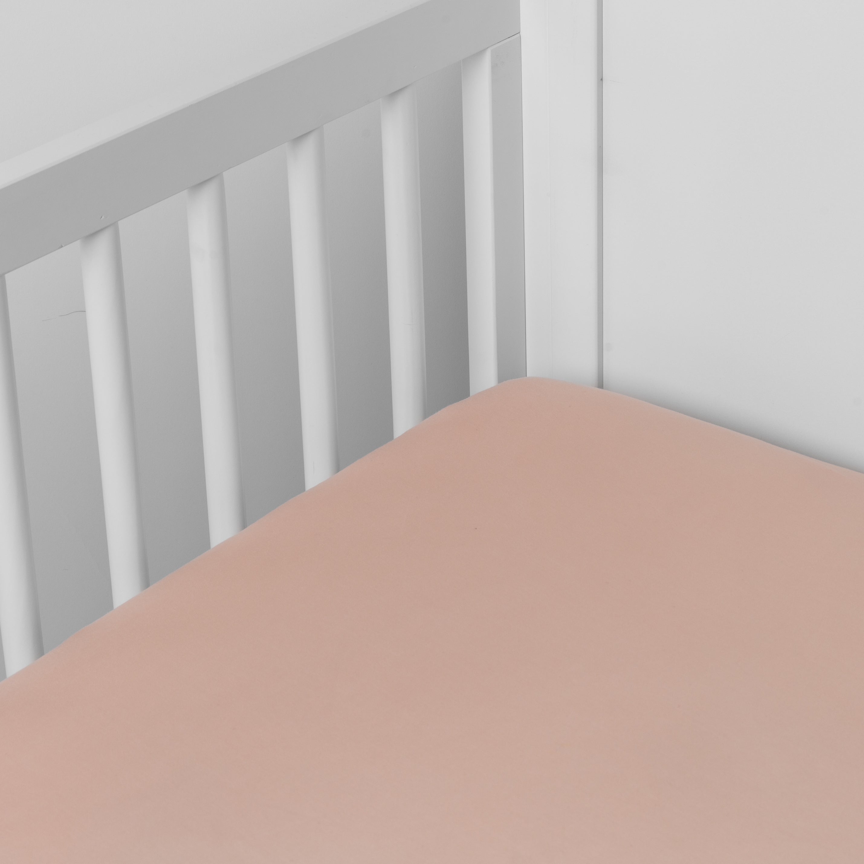 Rouge: crib sheet shown on a mattress shown from overhead into the corner of a crib.