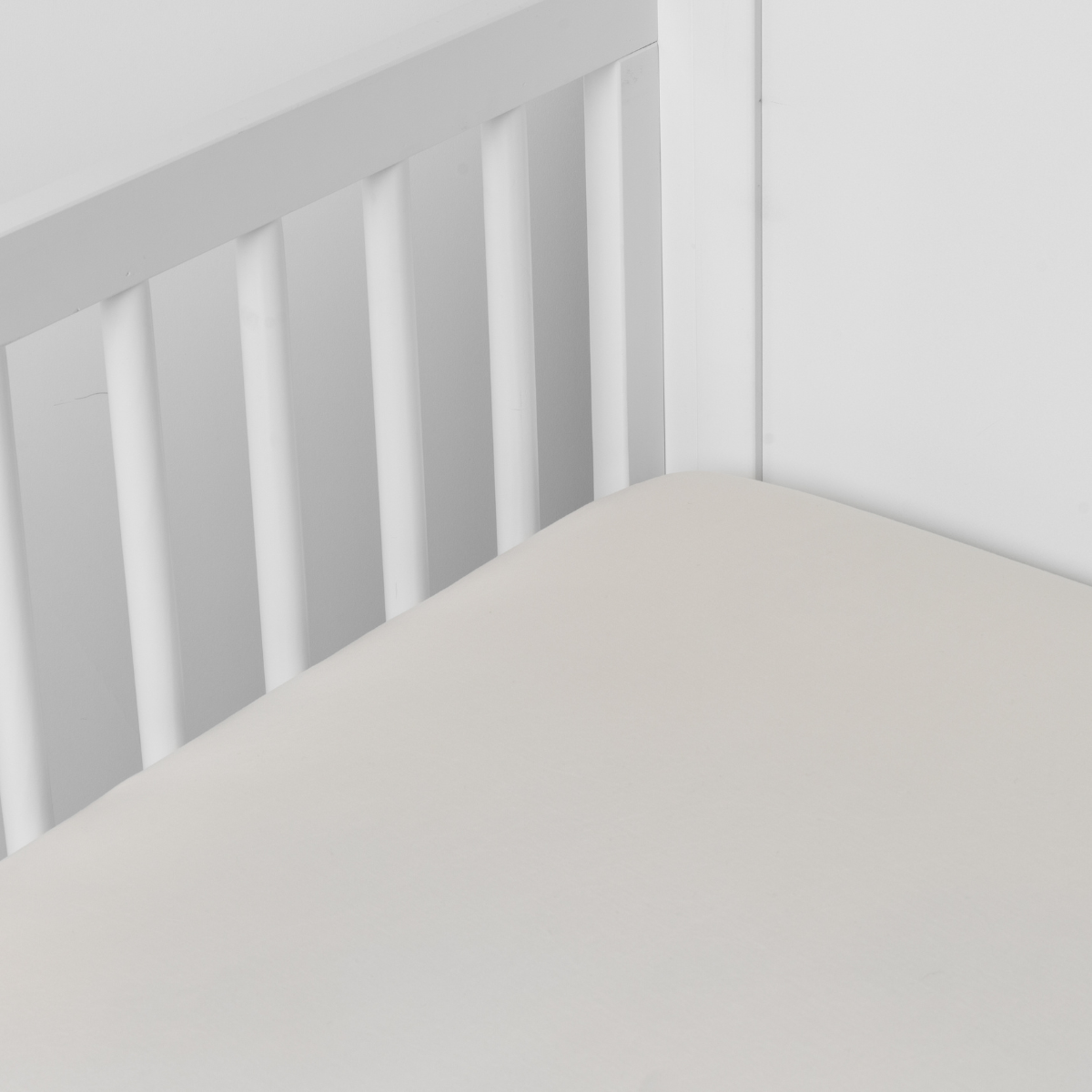 Parchment: crib sheet shown on a mattress shown from overhead into the corner of a crib.