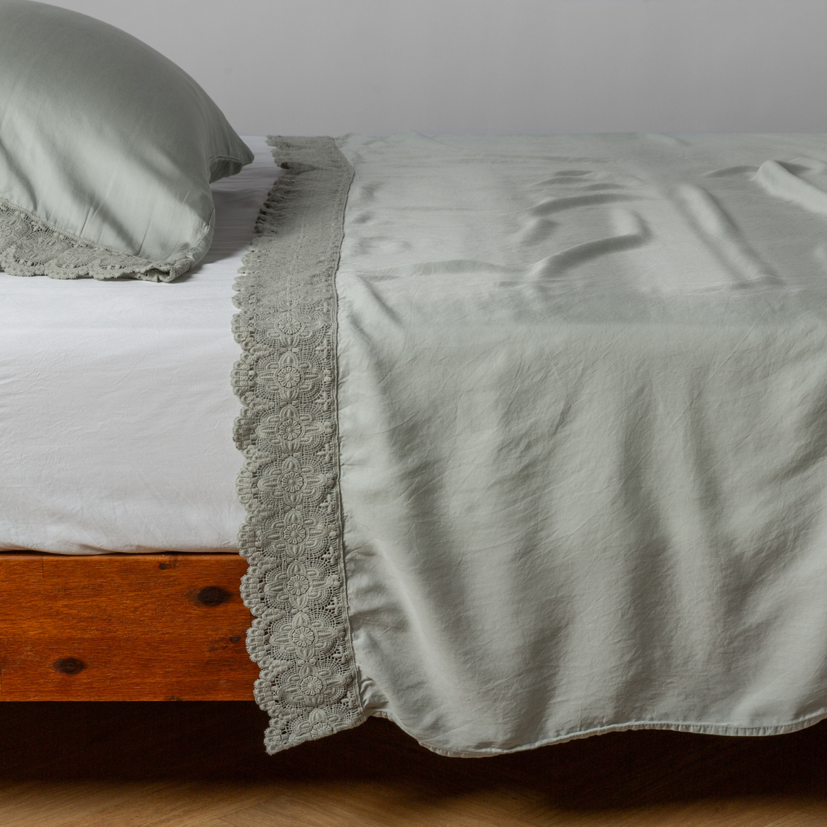 matching cotton lace trimmed flat sheet and pillowcase shown with simple white sheet - side view.