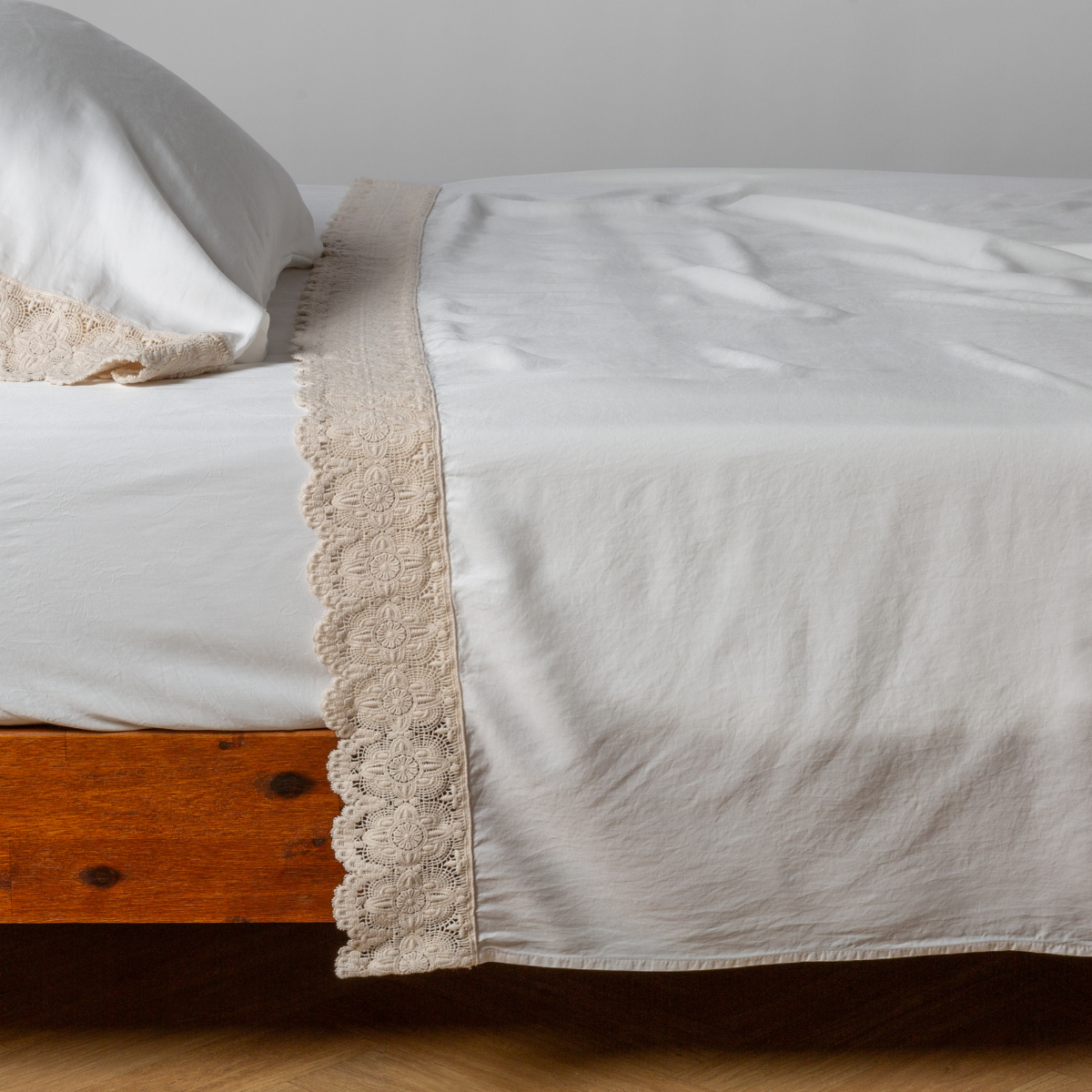 matching cotton lace trimmed flat sheet and pillowcase shown with simple white sheet - side view.