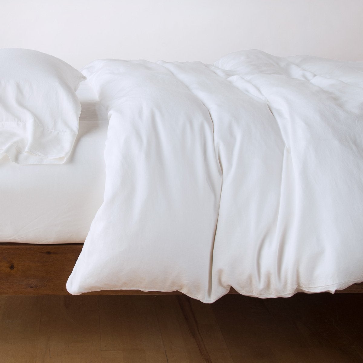 White: duvet cover with matching sleeping pillow and fitted sheet - side view.
