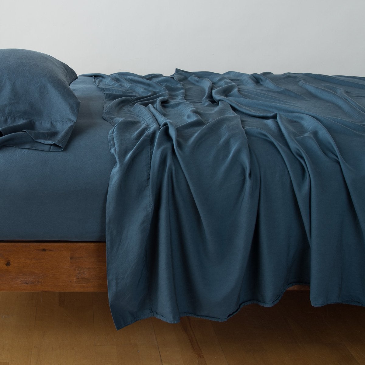 Midnight: fitted sheet with matching rumpled flat sheet and sleeping pillow - side view.