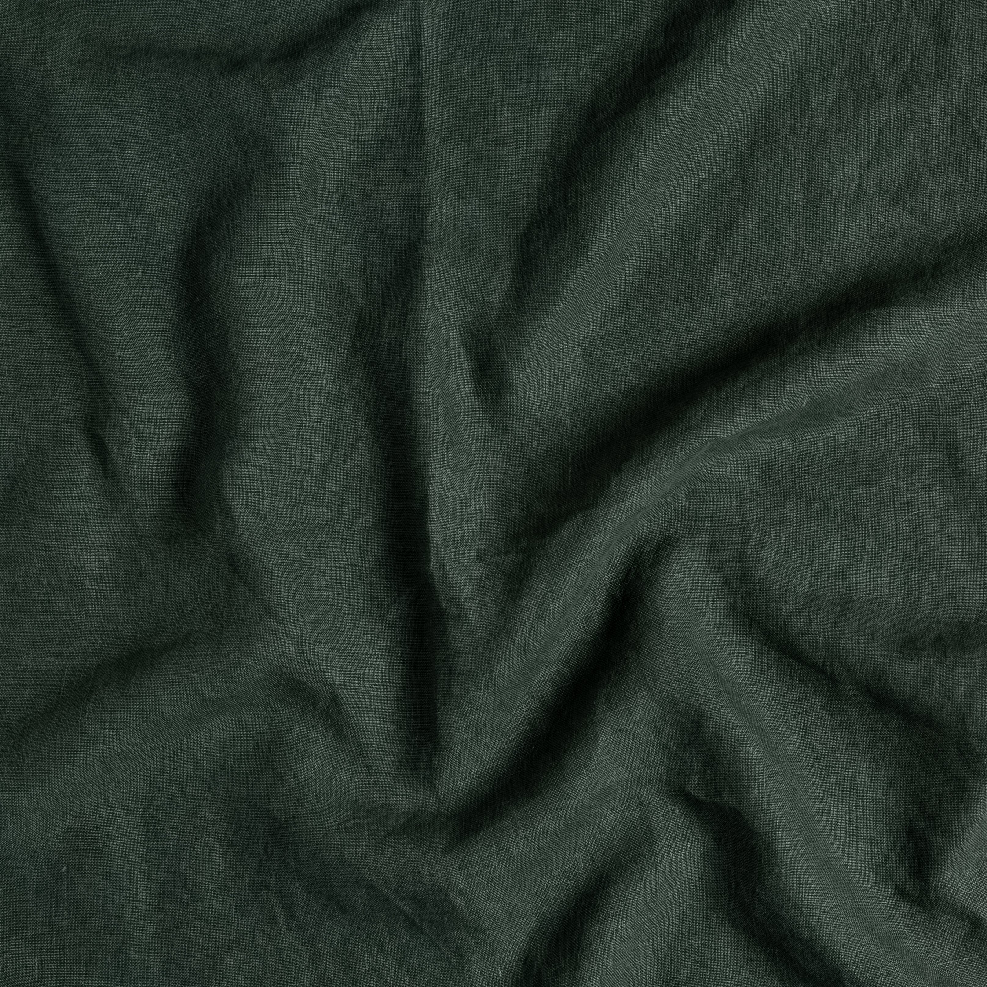 A close up of midweight linen in juniper, a dark green tone.