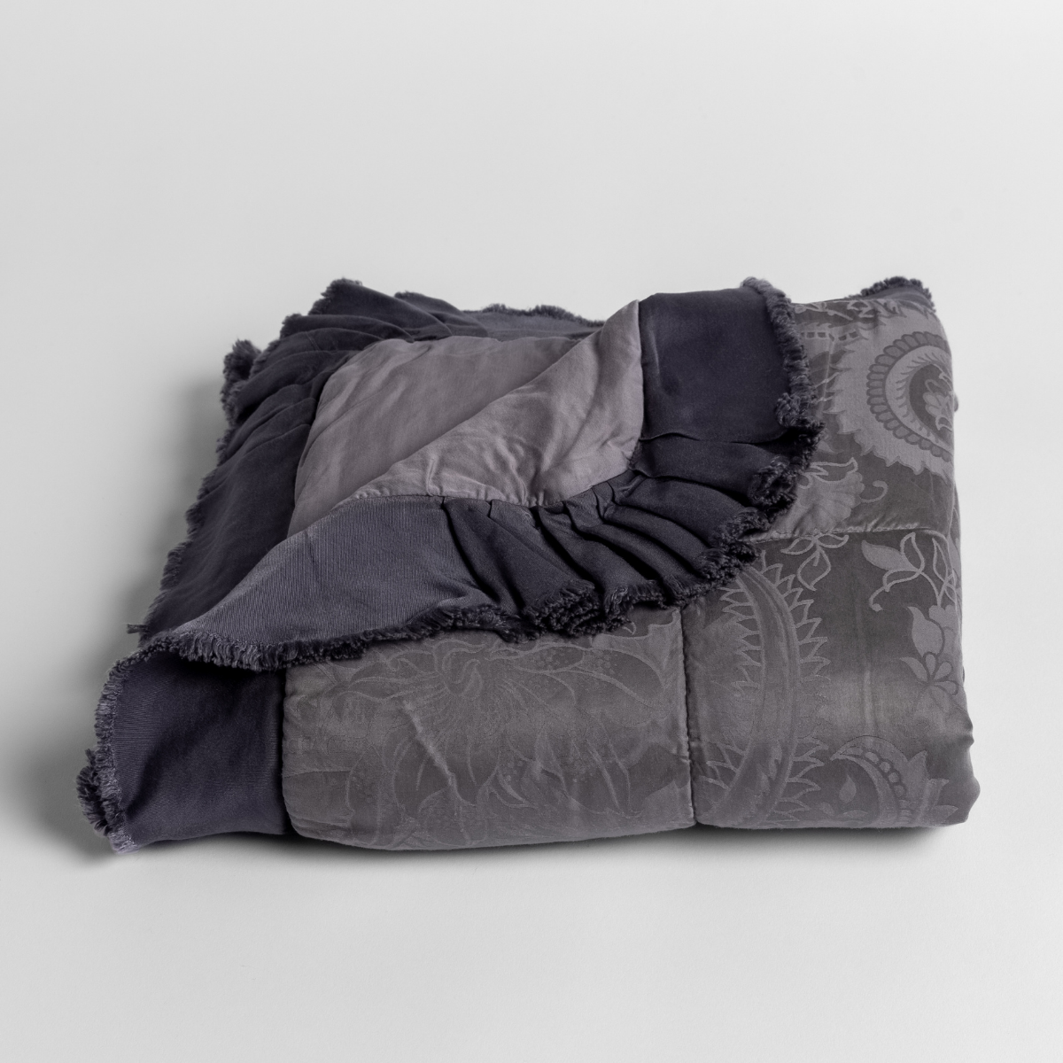a silk and tencel™ jacquard baby blanket folded and shot against a white background with the ruffled trim situated to be visible.