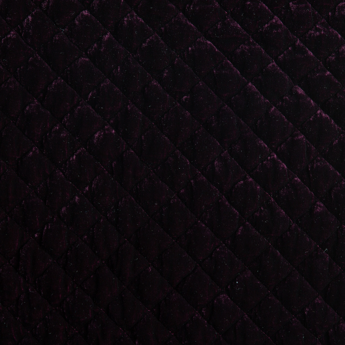 Fig: A close up of quilted silk velvet fabric in fig, a richly saturated purple-garnet.