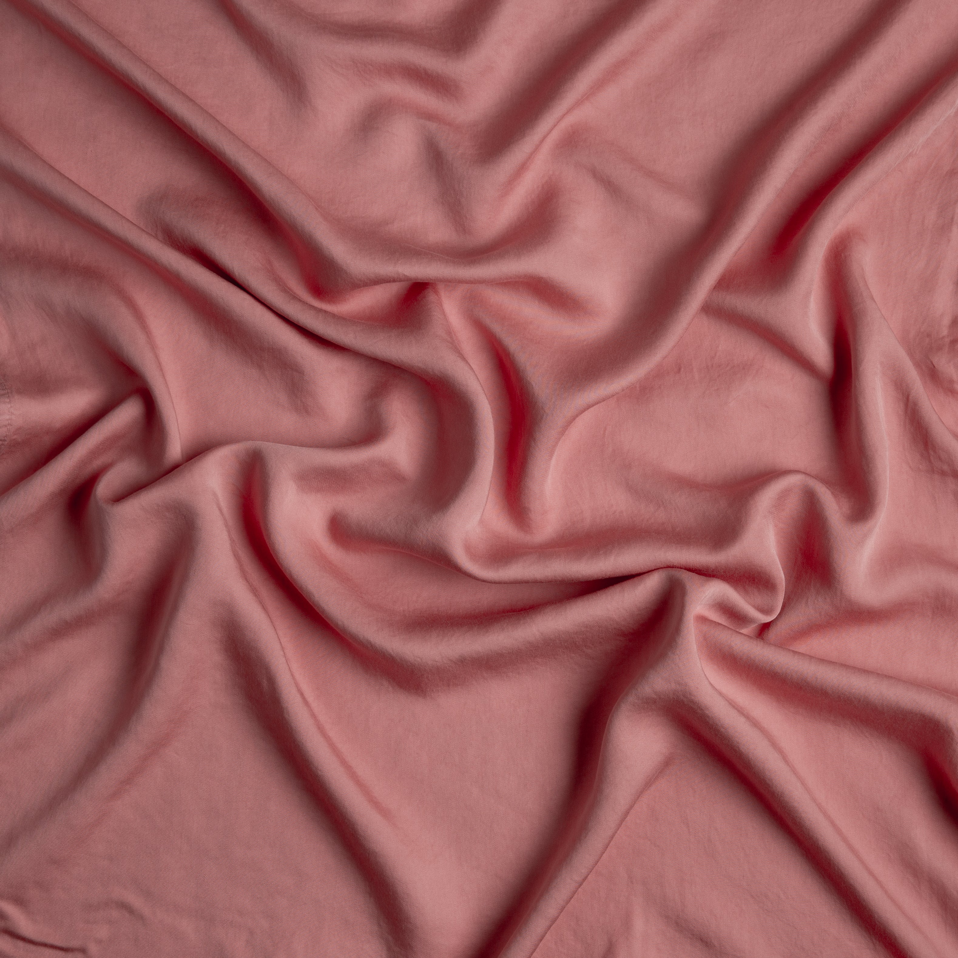 Poppy: A close up of Tencel™ fabric in poppy, a warm coral pink.