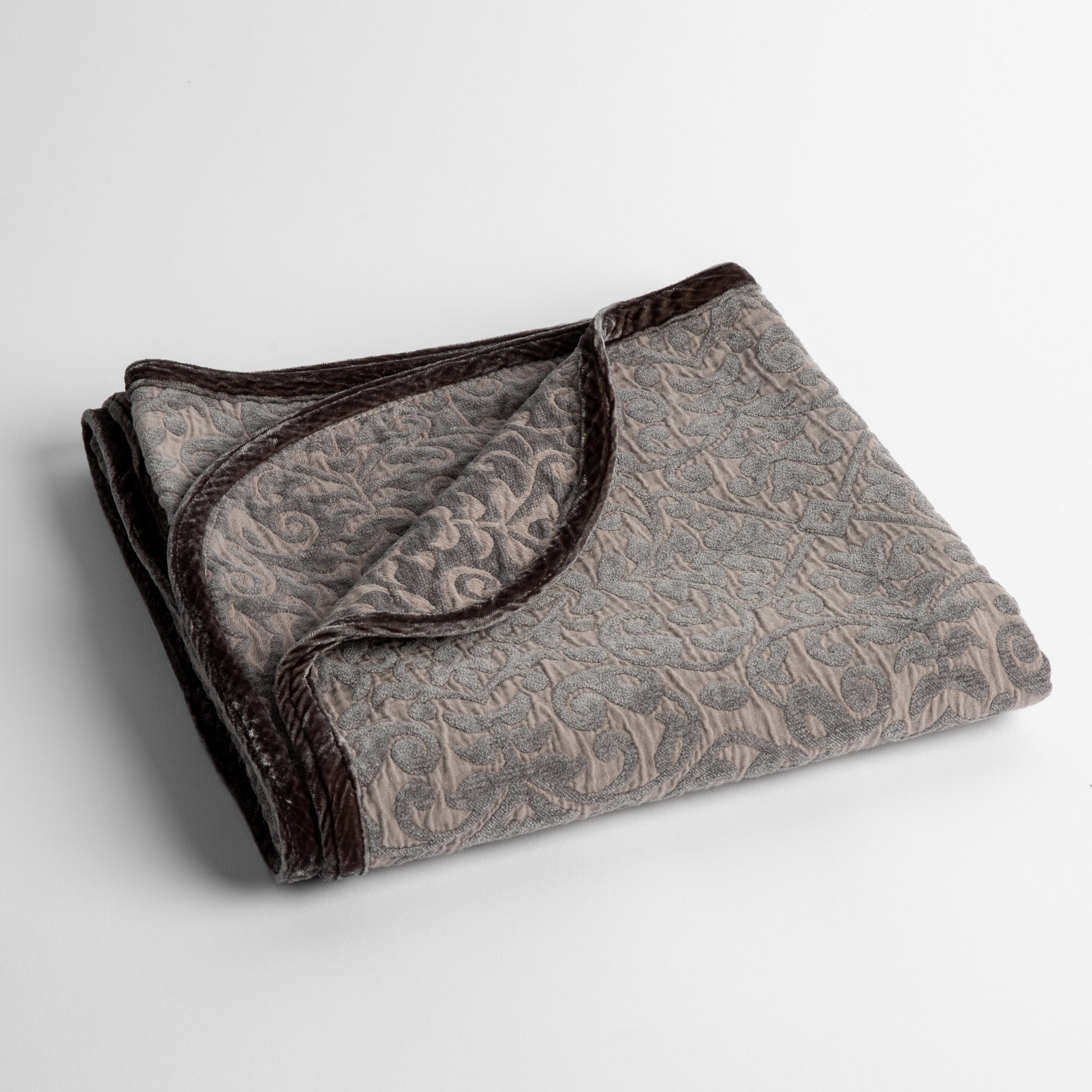 Moonlight: a folded cotton chenille baby blanket trimmed in silk velvet shot overhead at a slight angle against a white background.