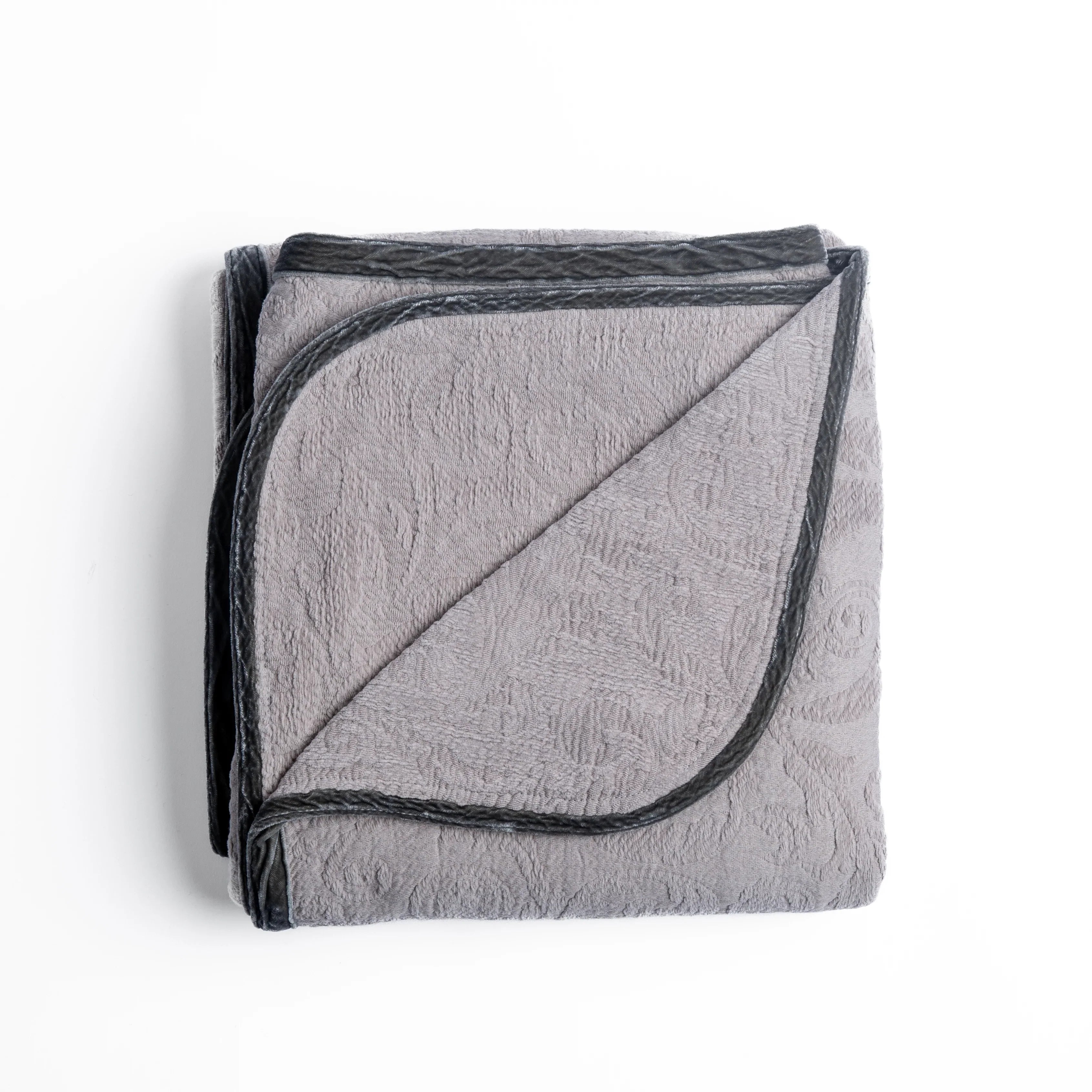 Fog: folded organic cotton damask throw blanket shown with the corner folded down to show silk velvet trim detail β overhead against a plain white background.