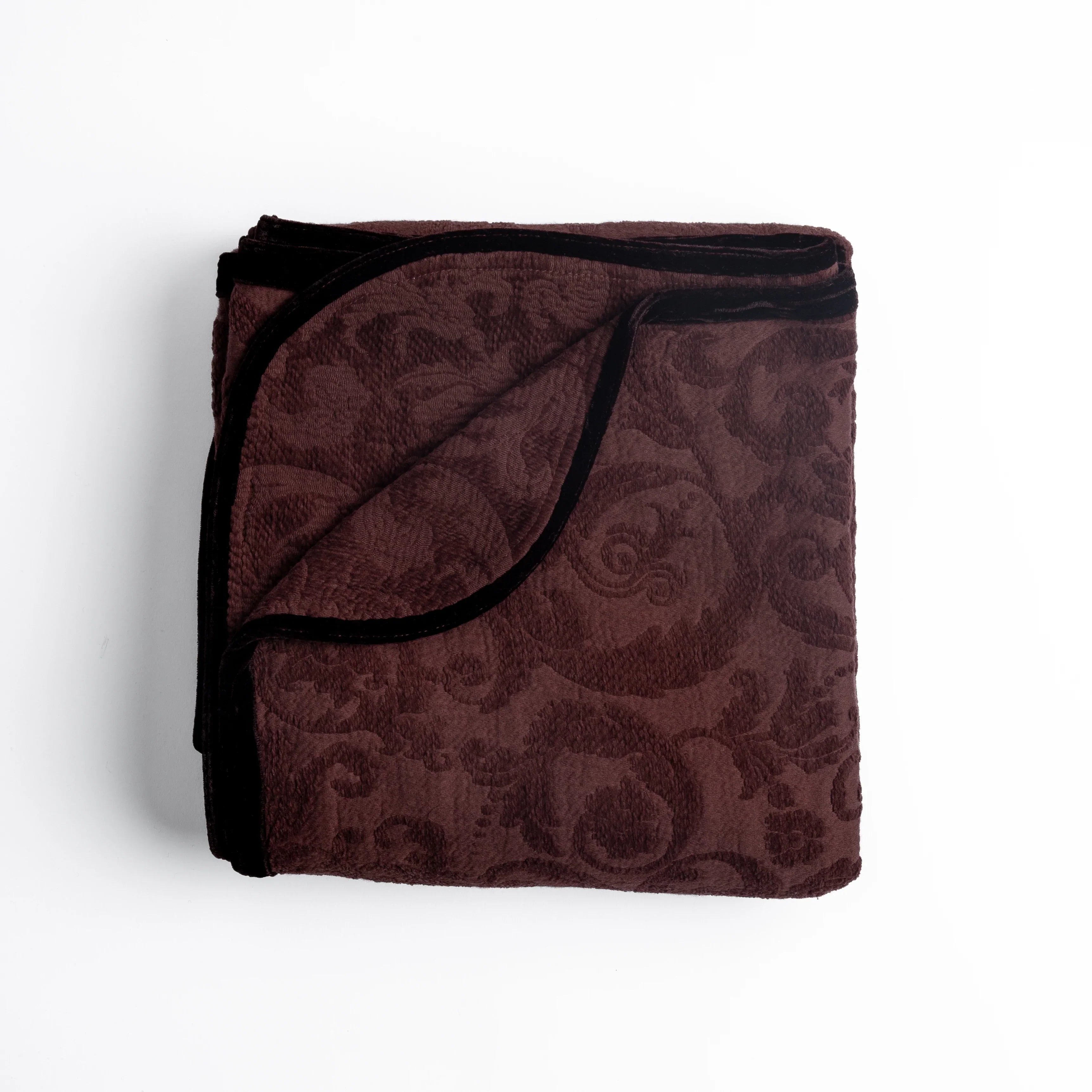 Mahogany: folded organic cotton damask throw blanket shown with the corner folded down to show silk velvet trim detail β overhead against a plain white background.