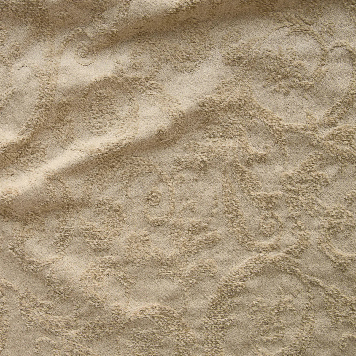 Honeycomb: A close up of Adele fabric in honeycomb, a warm golden tone. The fabric is rumpled to show the cotton damask texture.