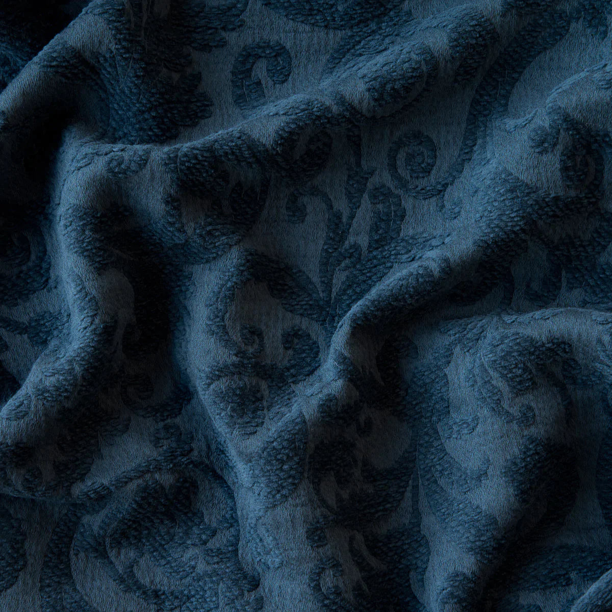 Midnight: A close up of Adele fabric in midnight, a rich indigo tone. The fabric is rumpled to show the cotton damask texture.