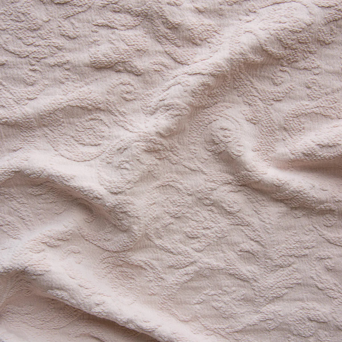 Pearl: A close up of Adele fabric in pearl, a nude-like, soft rose pink tone. The fabric is rumpled to show the cotton damask texture.