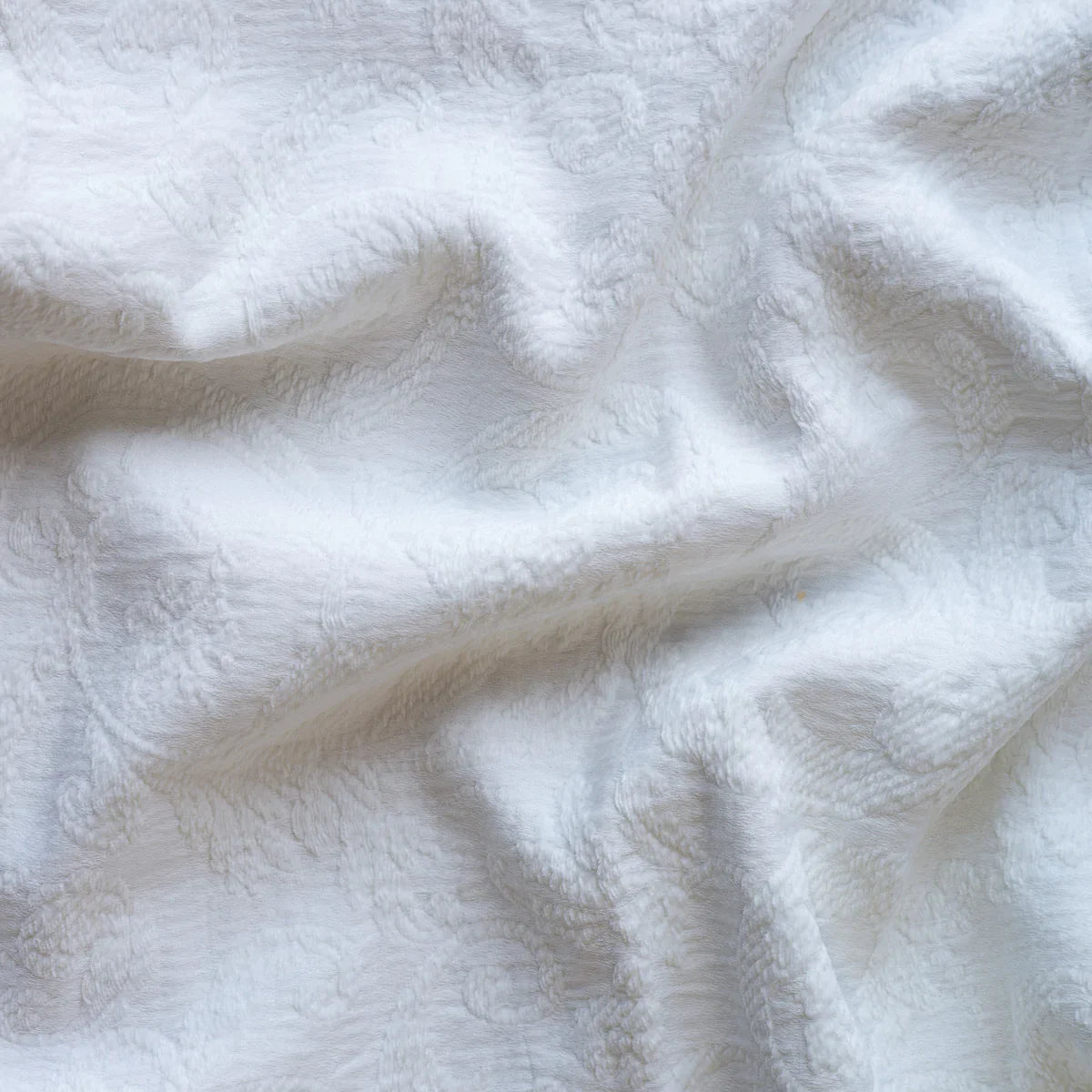 White: A close up of Adele fabric in white. The fabric is rumpled to show the cotton damask texture.