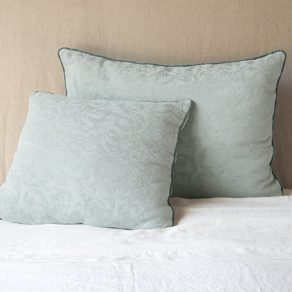 Eucalyptus: Two Adele shams, shown in euro and deluxe sizes, leaning against a neutral toned headboard on white bedding.