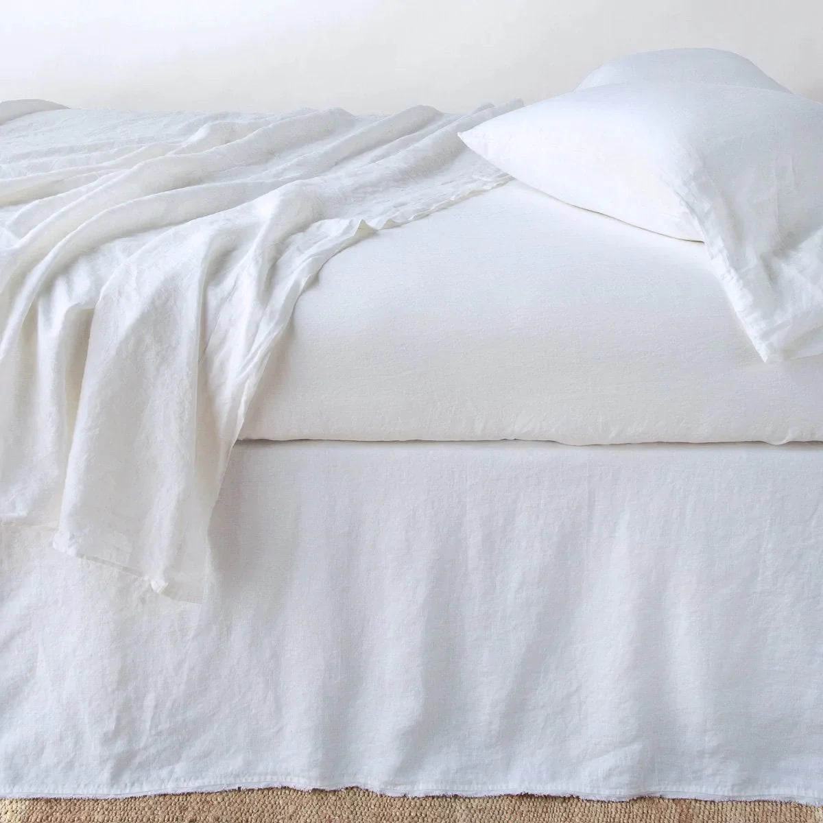 White: Austin bed skirt in white shown from the side on a bed with monochromatic sheeting, highlighting its tailored, ungathered style.