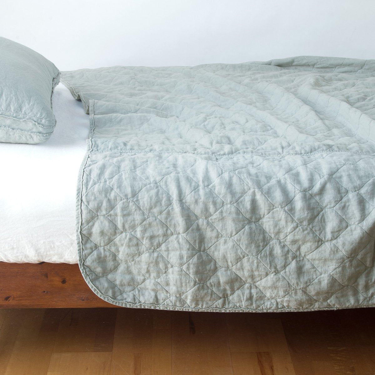 Eucalyptus: quilted midweight linen coverlet on a bed - side view.