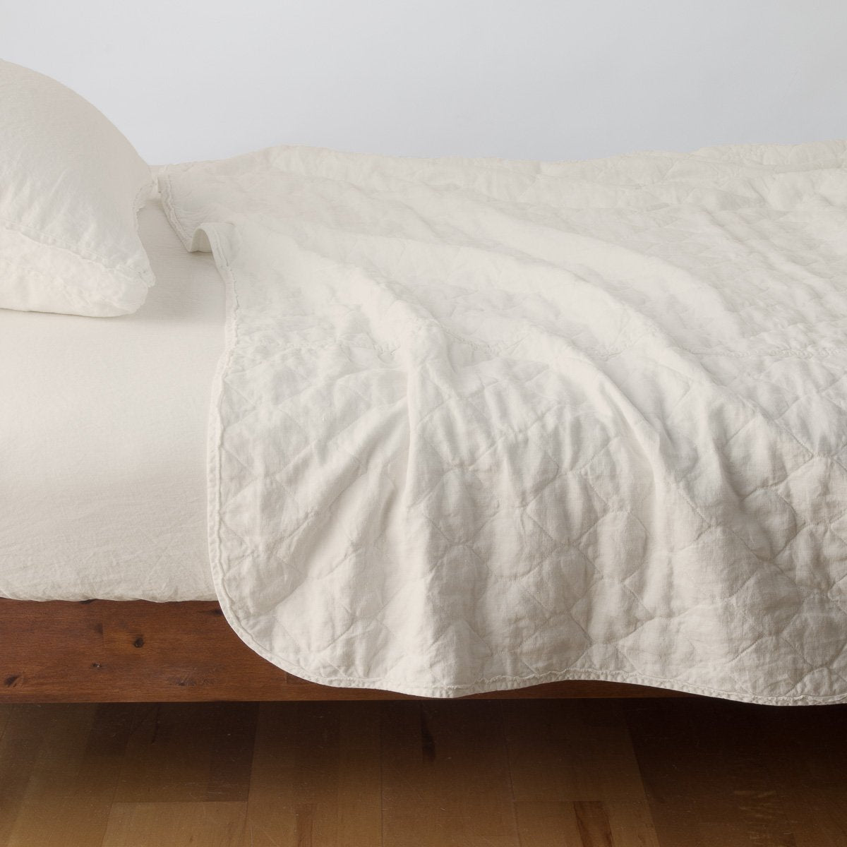 Parchment: quilted midweight linen coverlet on a bed - side view.