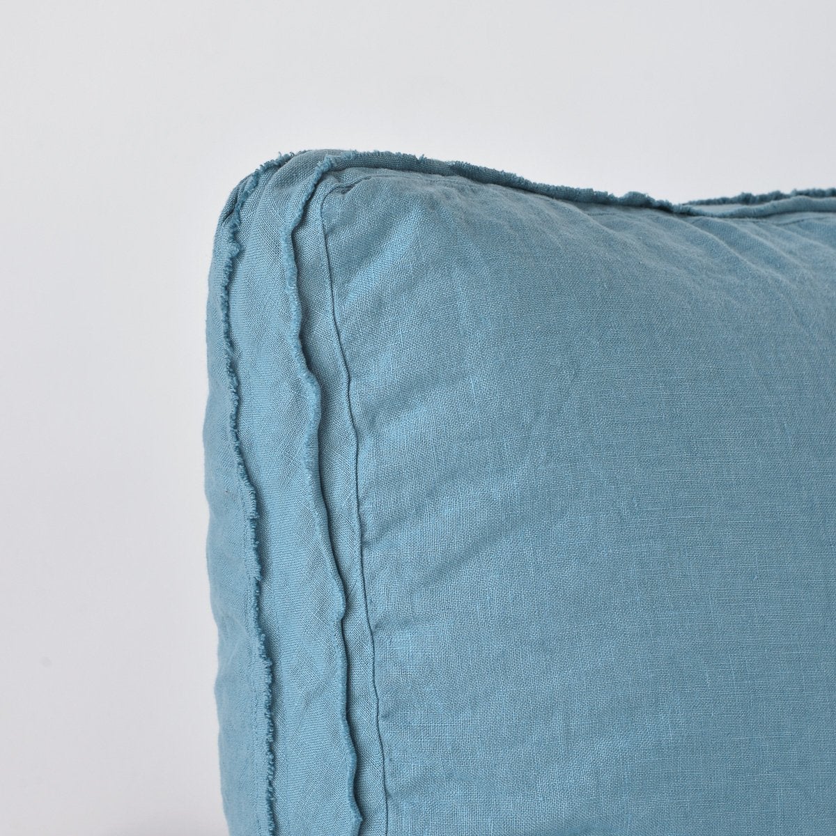 Cenote: Close-up angle of the corner of an Austin sham, highlighting the raw edge trim on either side of the gusset.