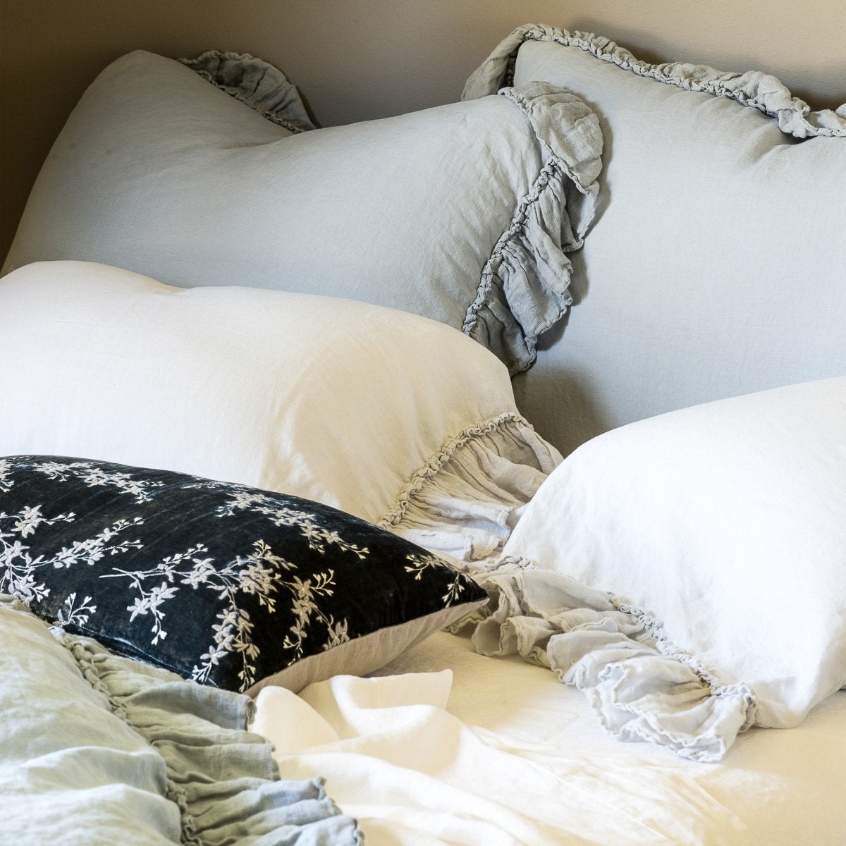 : Linen Whisper pillow cases in cloud, with matching shams and duvet cover in soft blues and greens - cropped three-quarter angle.