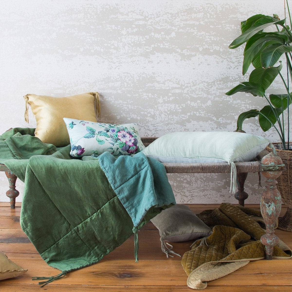 : Taline throw blanket in jade draped over a wooden bench, one edge folded back to reveal midweight linen reverse.