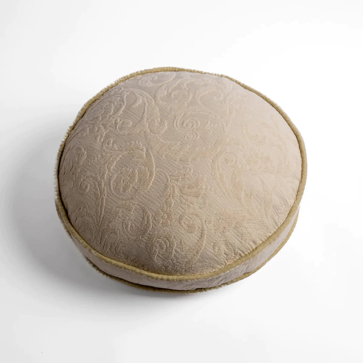 Parchment: Organic cotton damask round pillow with silk velvet trim on white background — overhead angle.