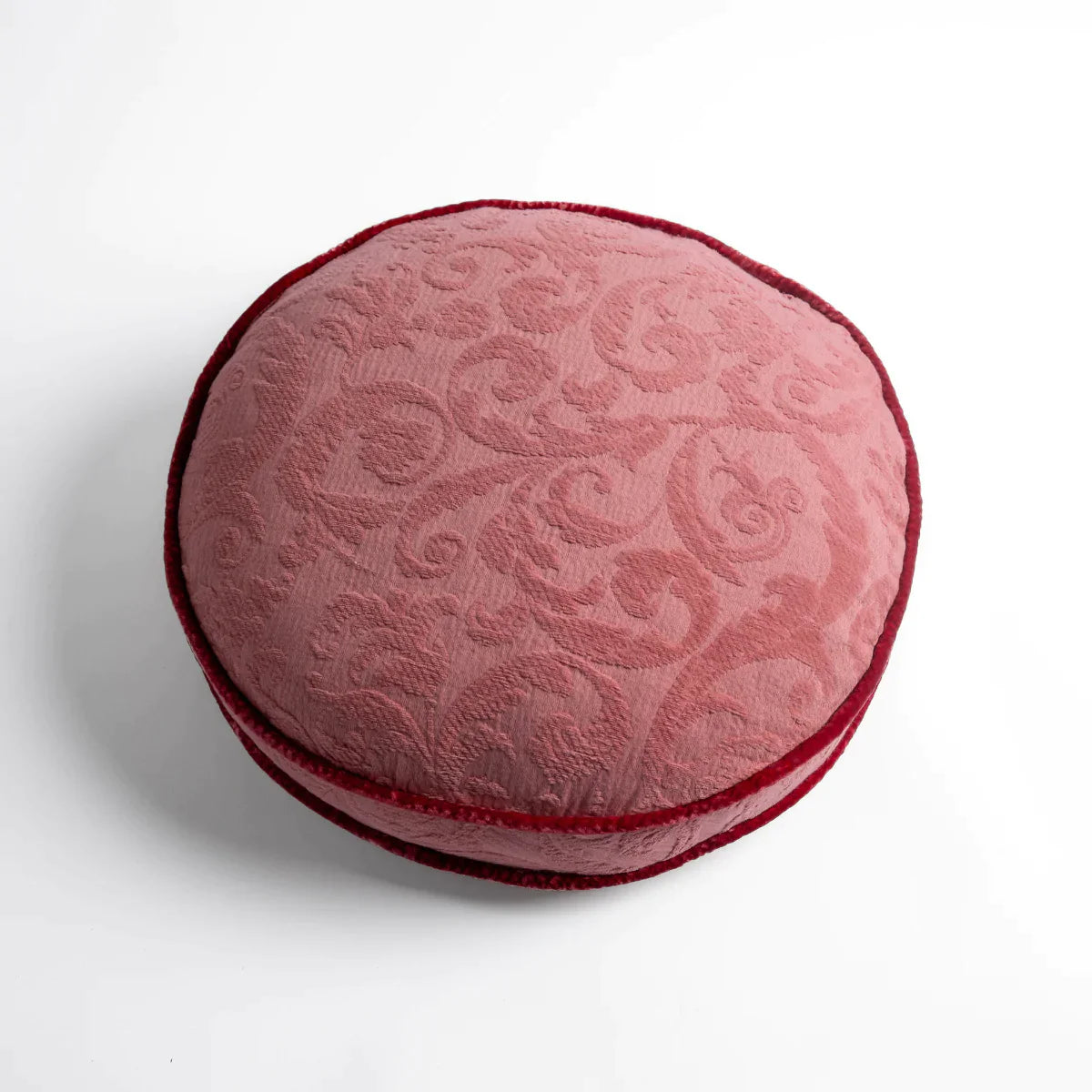 Poppy: Organic cotton damask round pillow with silk velvet trim on white background — overhead angle.