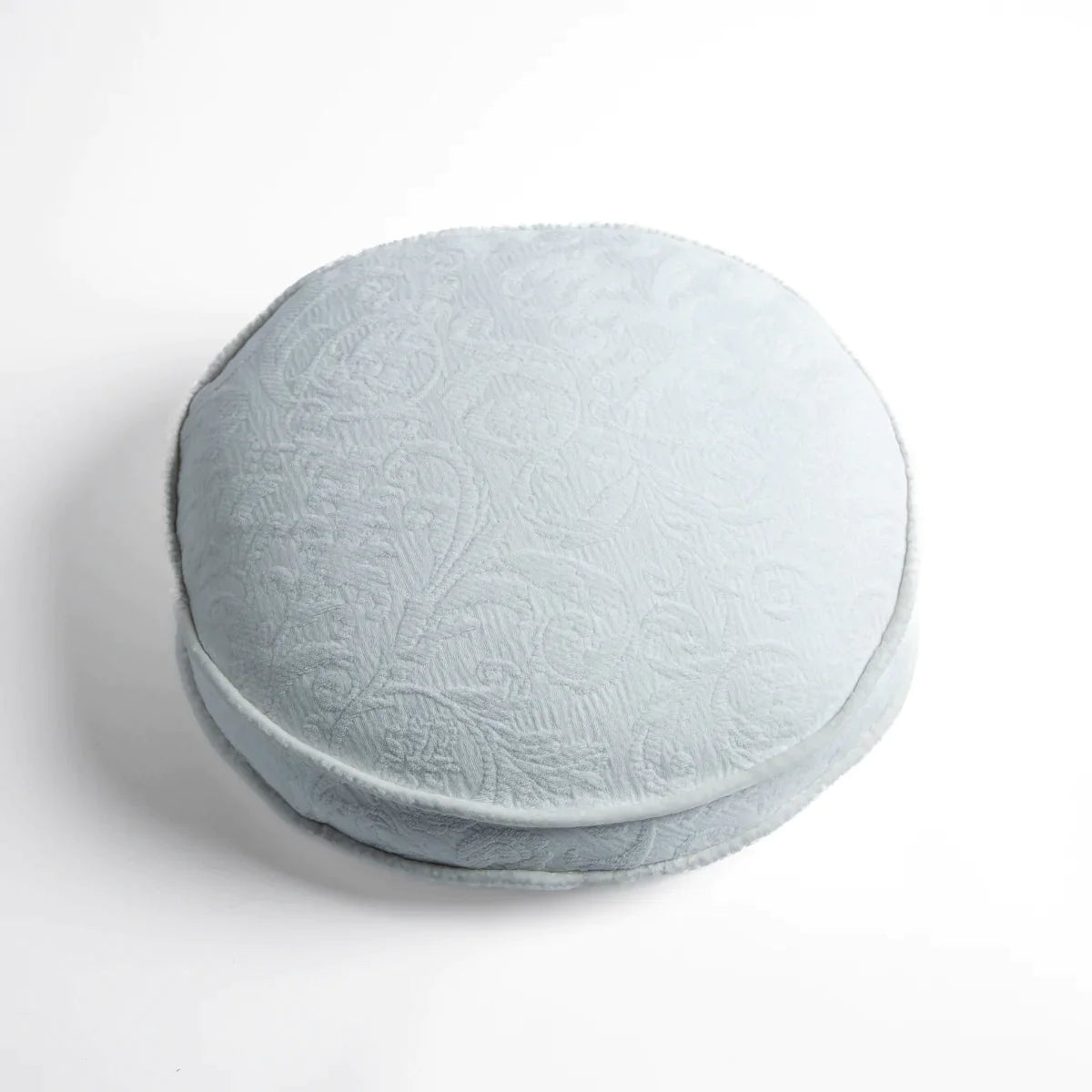 Winter White: Organic cotton damask round pillow with silk velvet trim on white background — overhead angle.