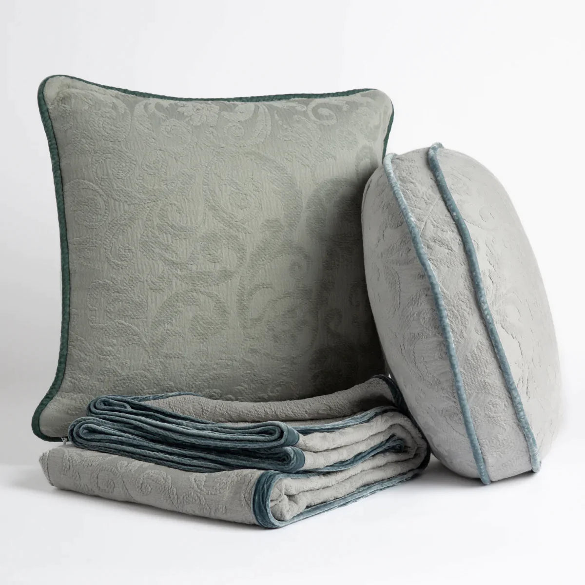 : Organic cotton damask throw pillows and throw blanket on a white background.