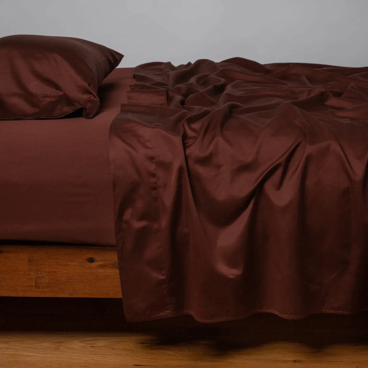 Mahogany: Cotton sateen fitted sheet shown with matching flat sheet and sleeping pillow - side view.