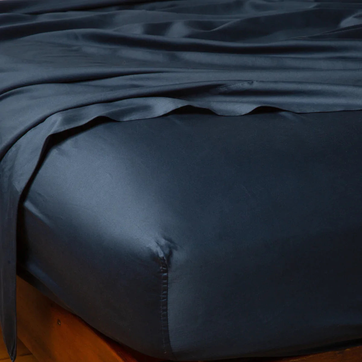 Midnight: Cotton sateen fitted sheet shown from the top corner, highlighting the shine of the fabric.