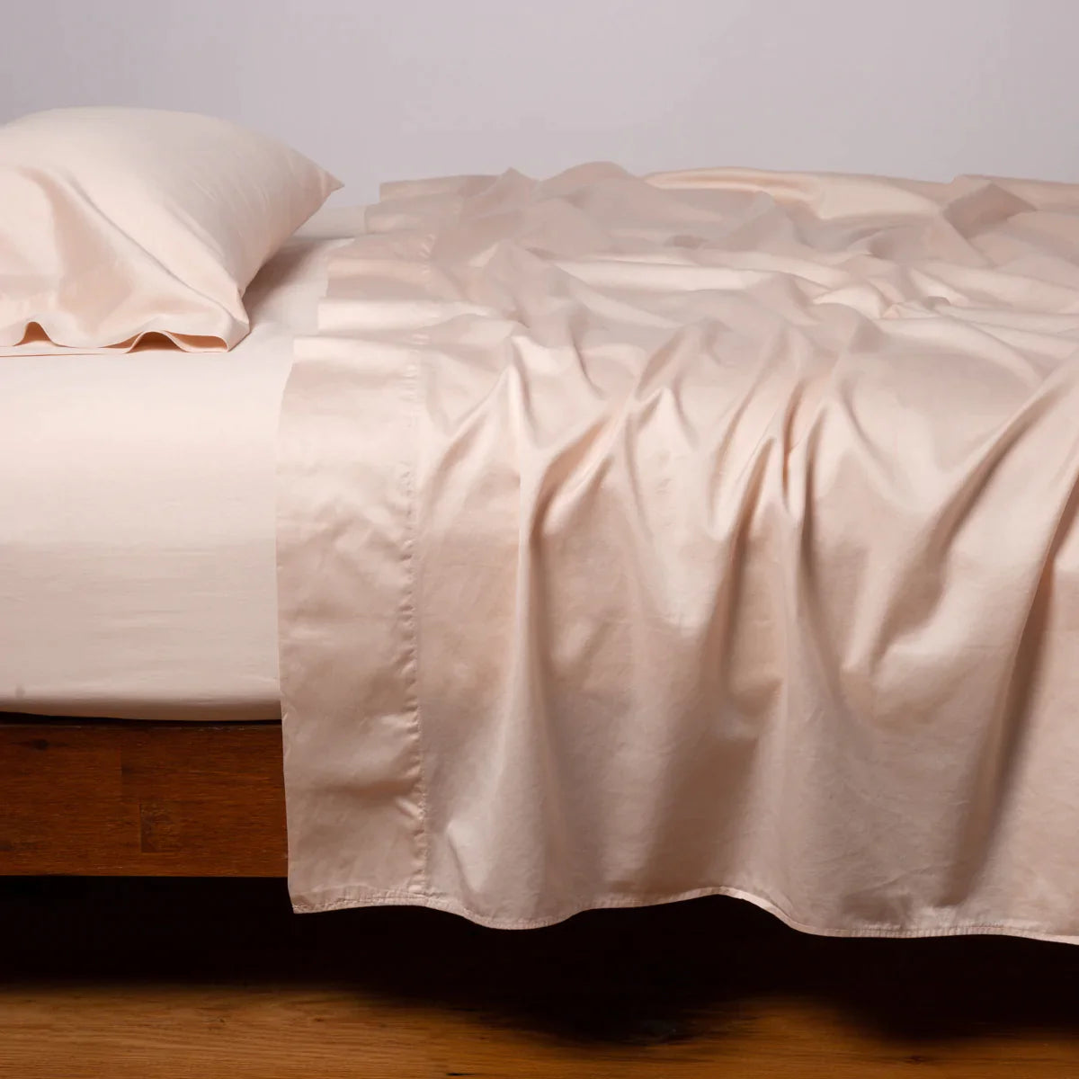 Pearl: Cotton sateen fitted sheet shown with matching flat sheet and sleeping pillow - side view.