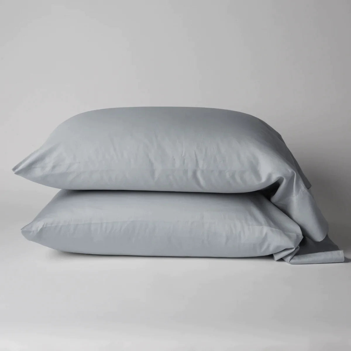Cloud: Two cotton sateen sleeping pillows, stacked neatly against a white backdrop - side view.