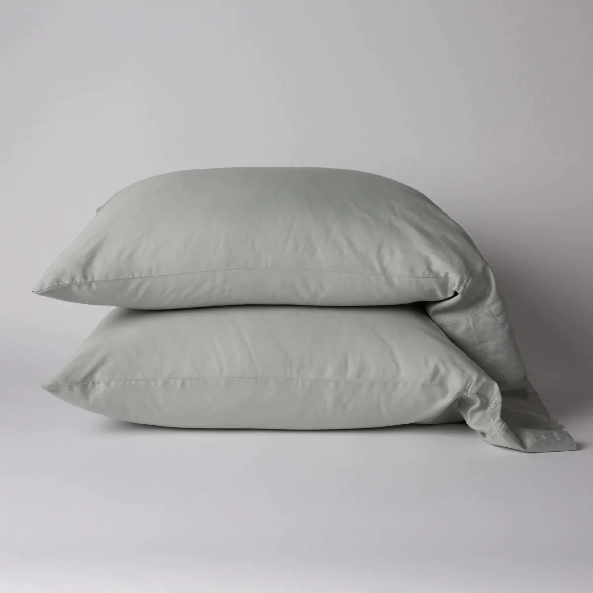 Eucalyptus: Two cotton sateen sleeping pillows, stacked neatly against a white backdrop - side view.