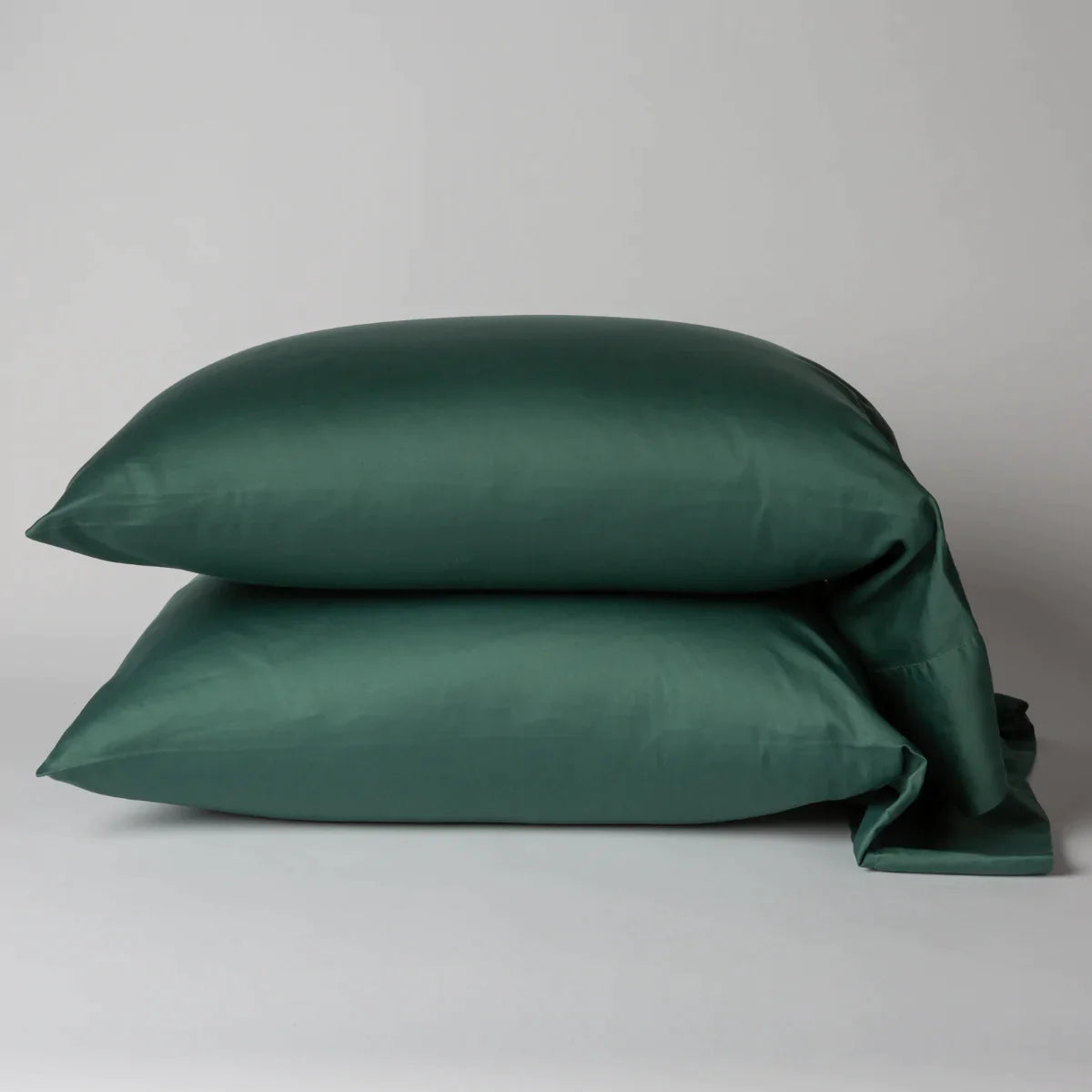 Jade: Two cotton sateen sleeping pillows, stacked neatly against a white backdrop - side view.