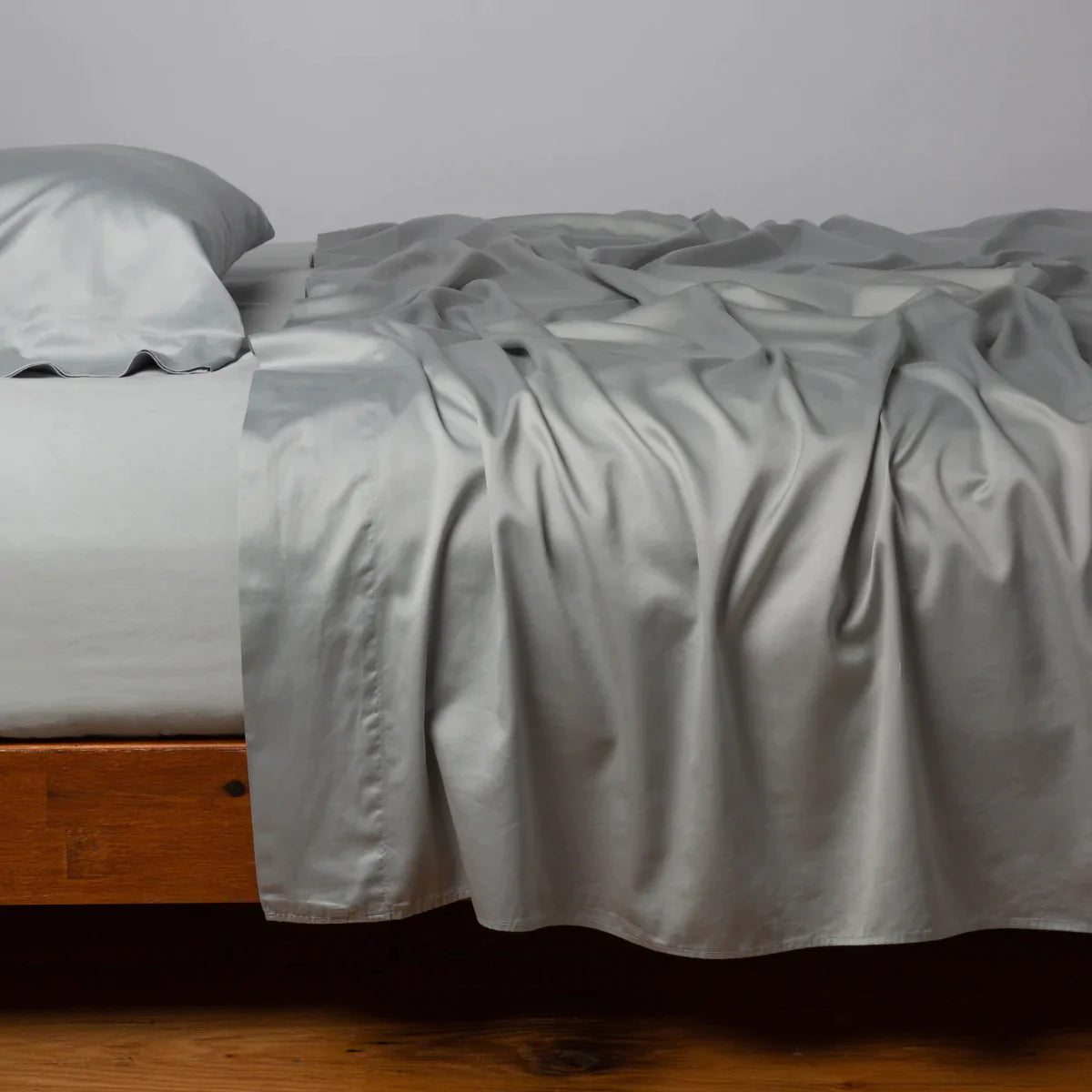 Mineral: Cotton sateen sleeping pillow, on a bed with matching sheets - side view.