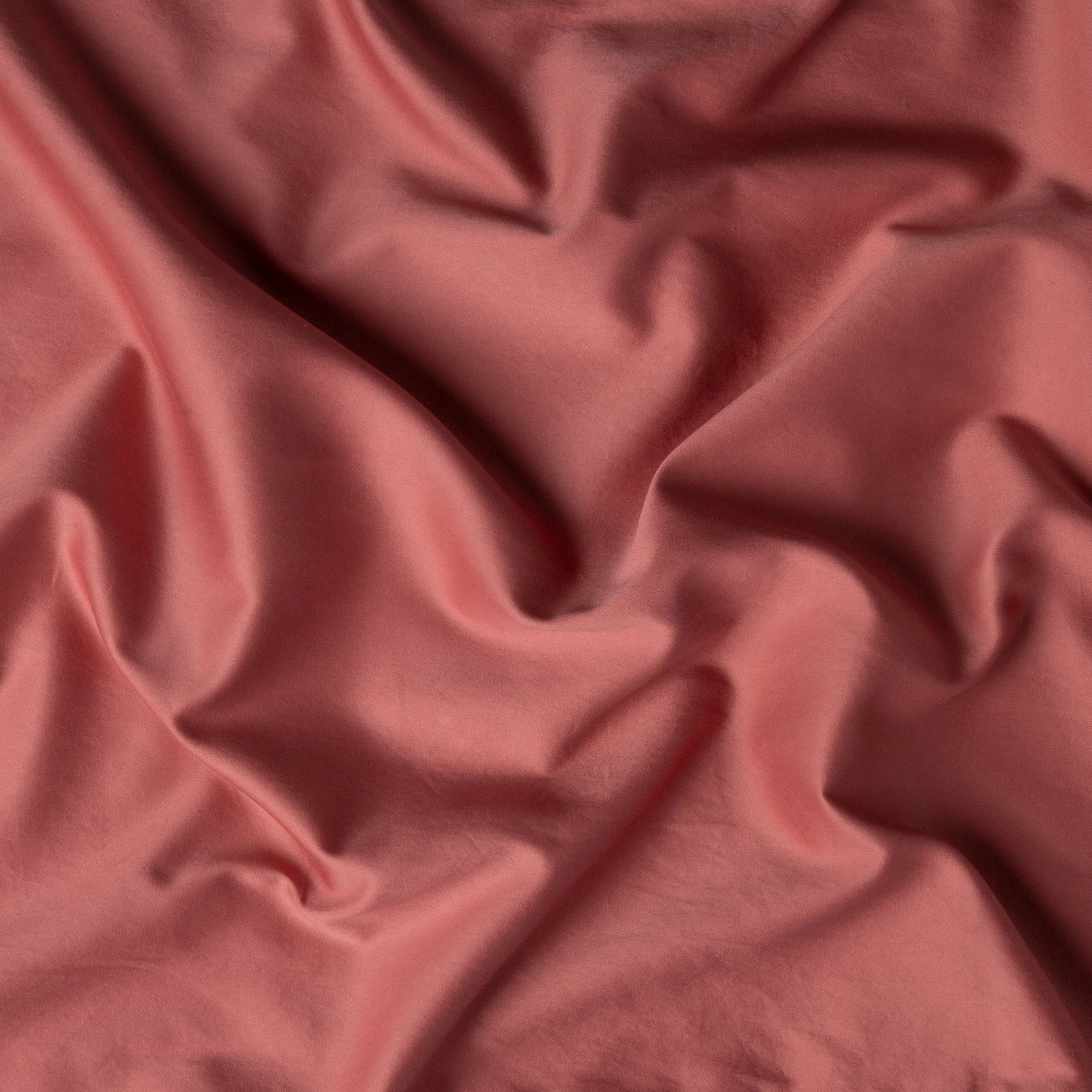 Poppy: A close up of cotton sateen fabric in poppy, a warm coral pink.