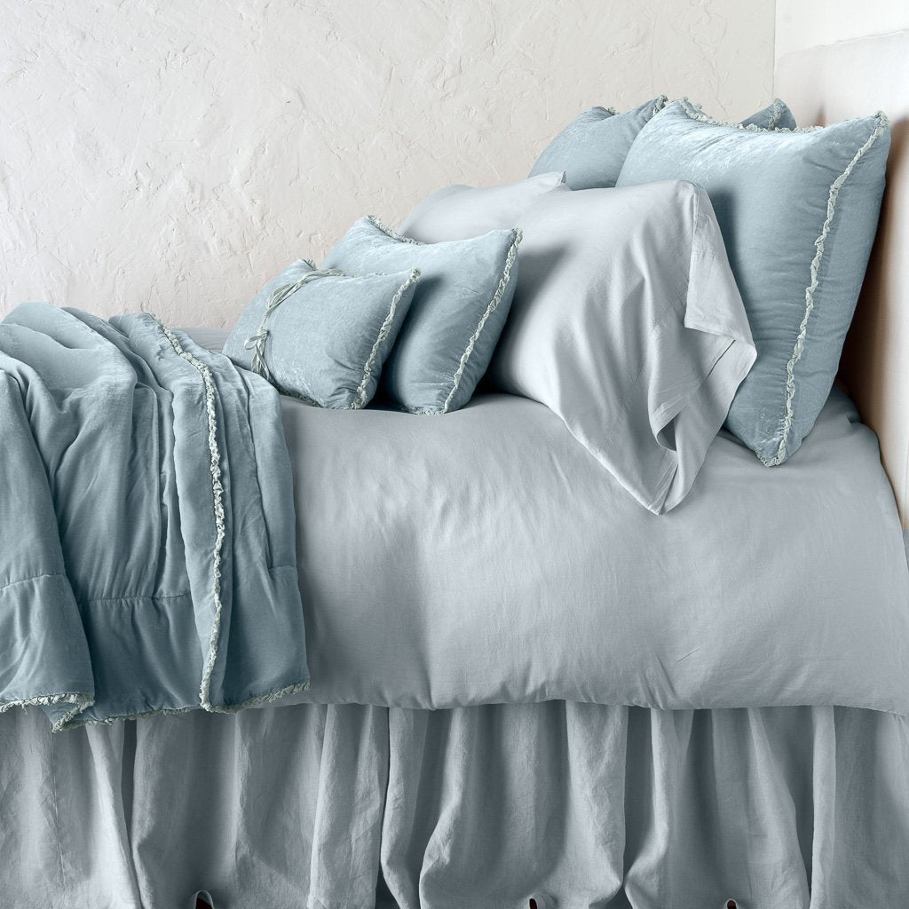 Cloud: Silk velvet throw blanket with petite ruffle, draped across a monochromatic bed - side view.