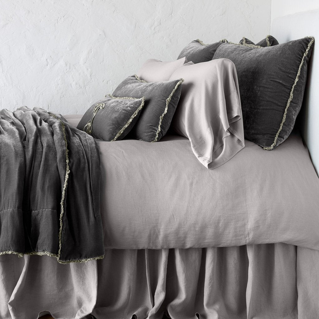 Fog: Silk velvet throw blanket with petite ruffle, draped across a monochromatic bed - side view.