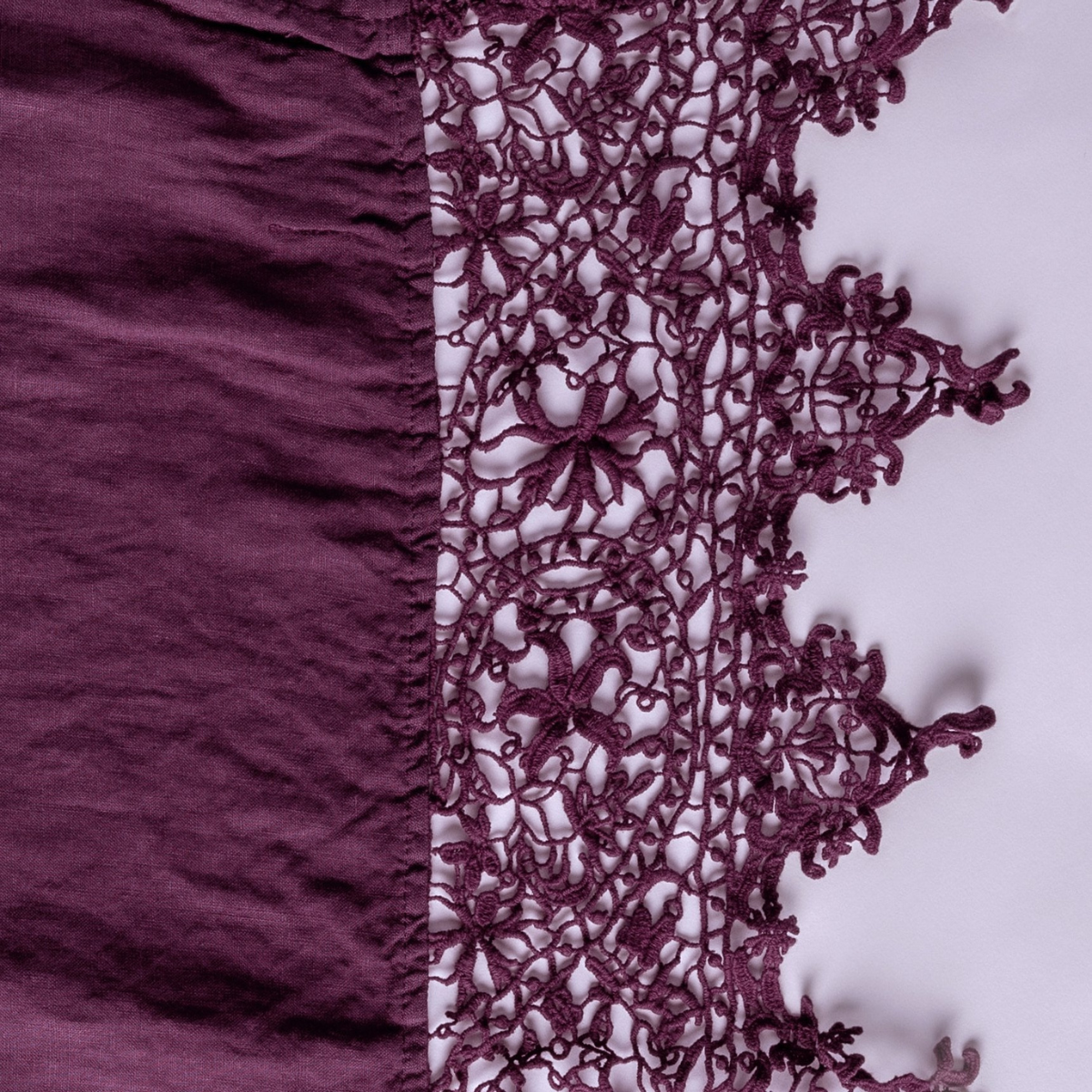 Fig: A close up of Frida, an antique cotton lace trim on a linen body, shown in fig, a richly saturated purple-garnet.