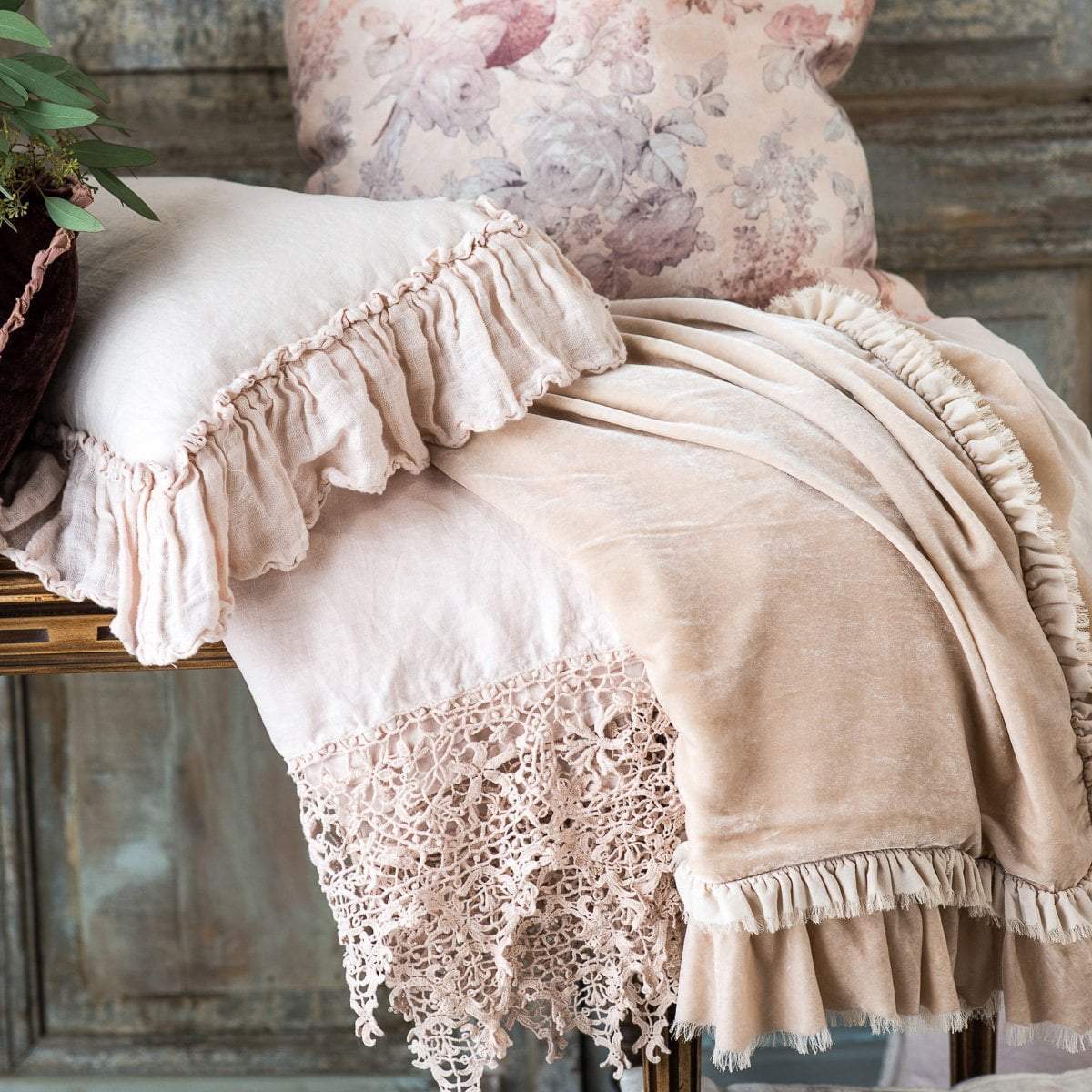 : Close up of a Pearl Frida flat sheet folded and draped over a table and stacked under monochromatic and ruffled accessory pieces.