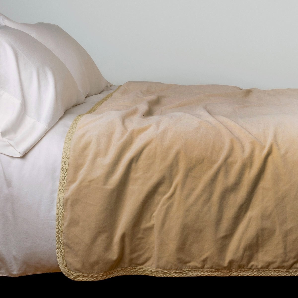Honeycomb: Cotton velvet bed end sized blanket, draped on a white bed - side view.