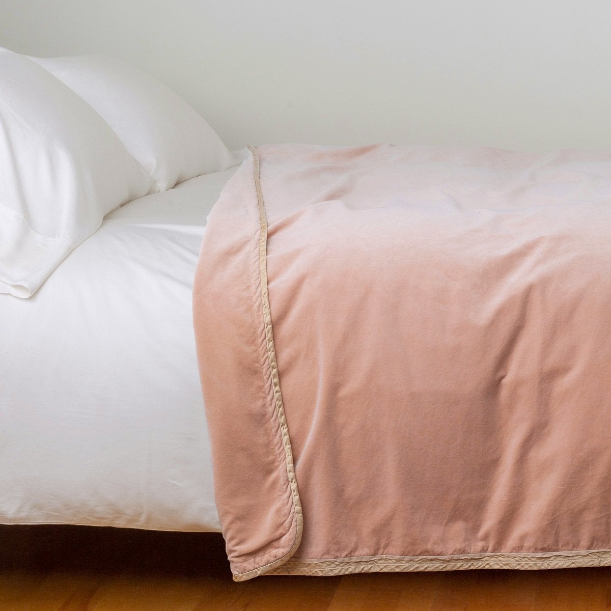 Rouge: Cotton velvet blanket, draped on a white bed with corner folded back - side view.