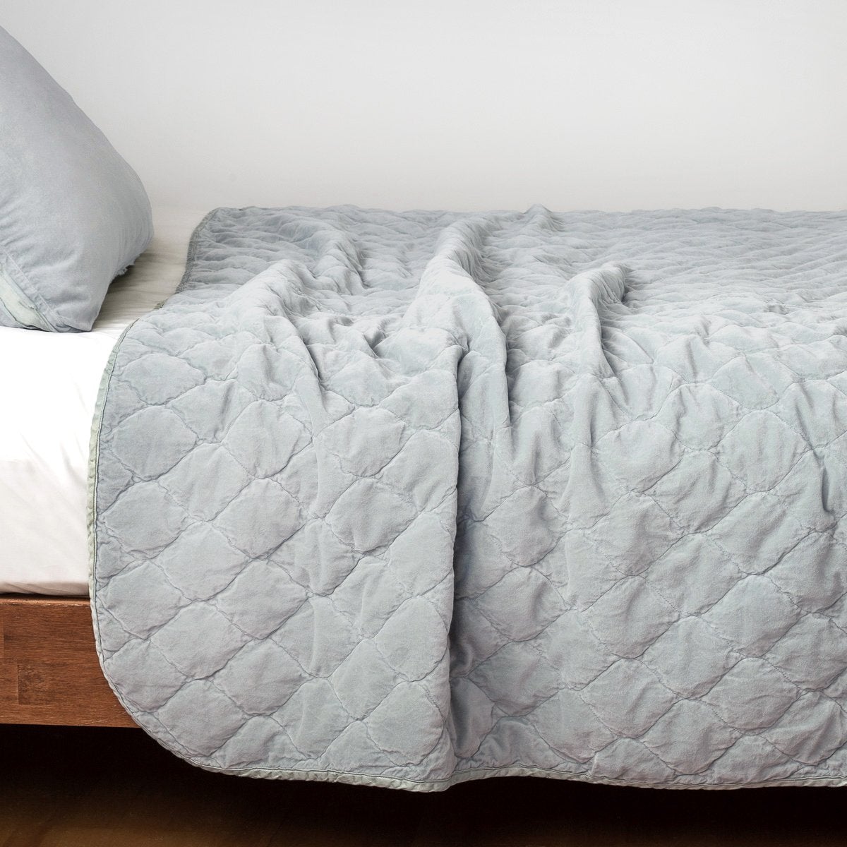 Cloud: Quilted cotton velvet coverlet draped over a white fitted sheet - side view.