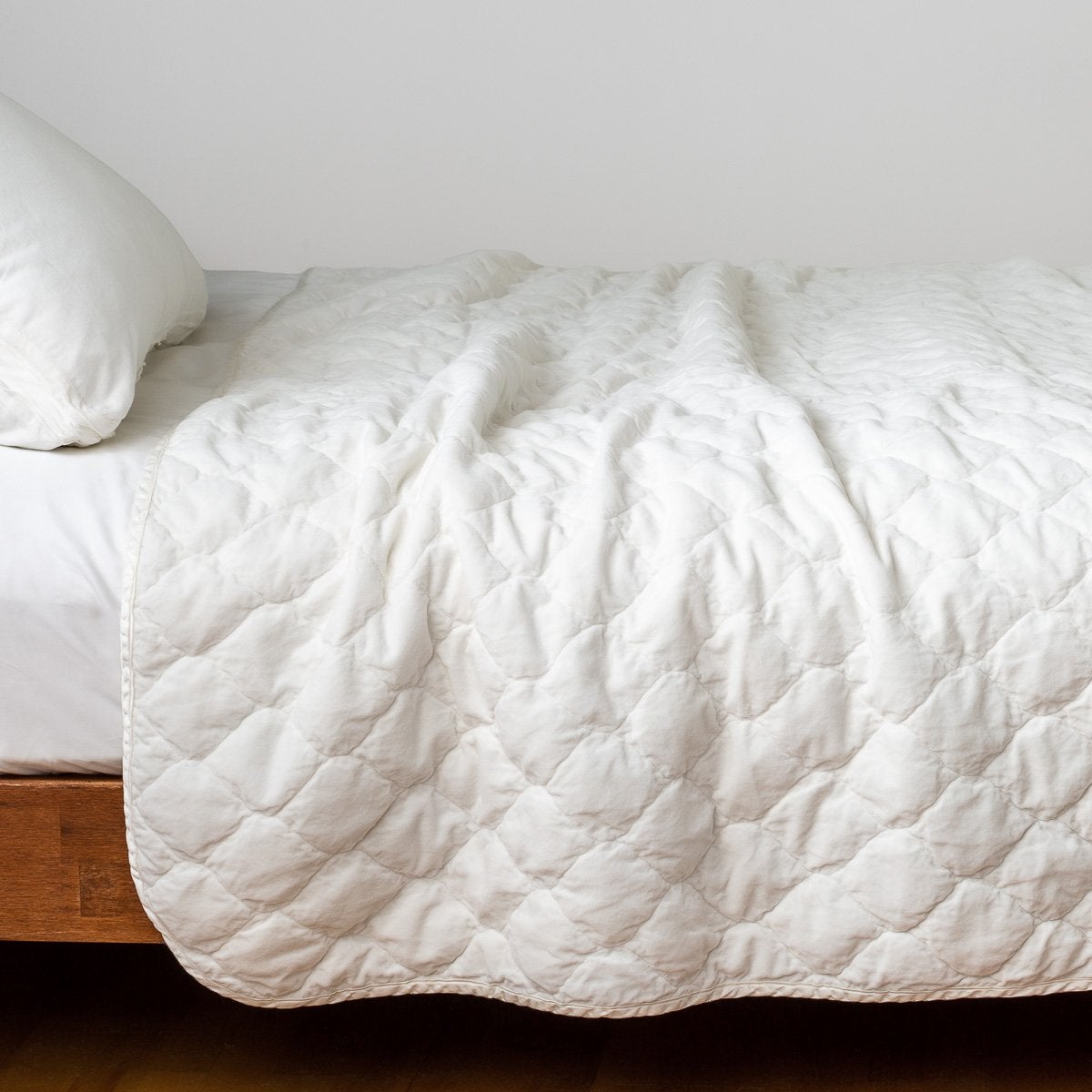 Winter White: Quilted cotton velvet coverlet draped over a white fitted sheet - side view.