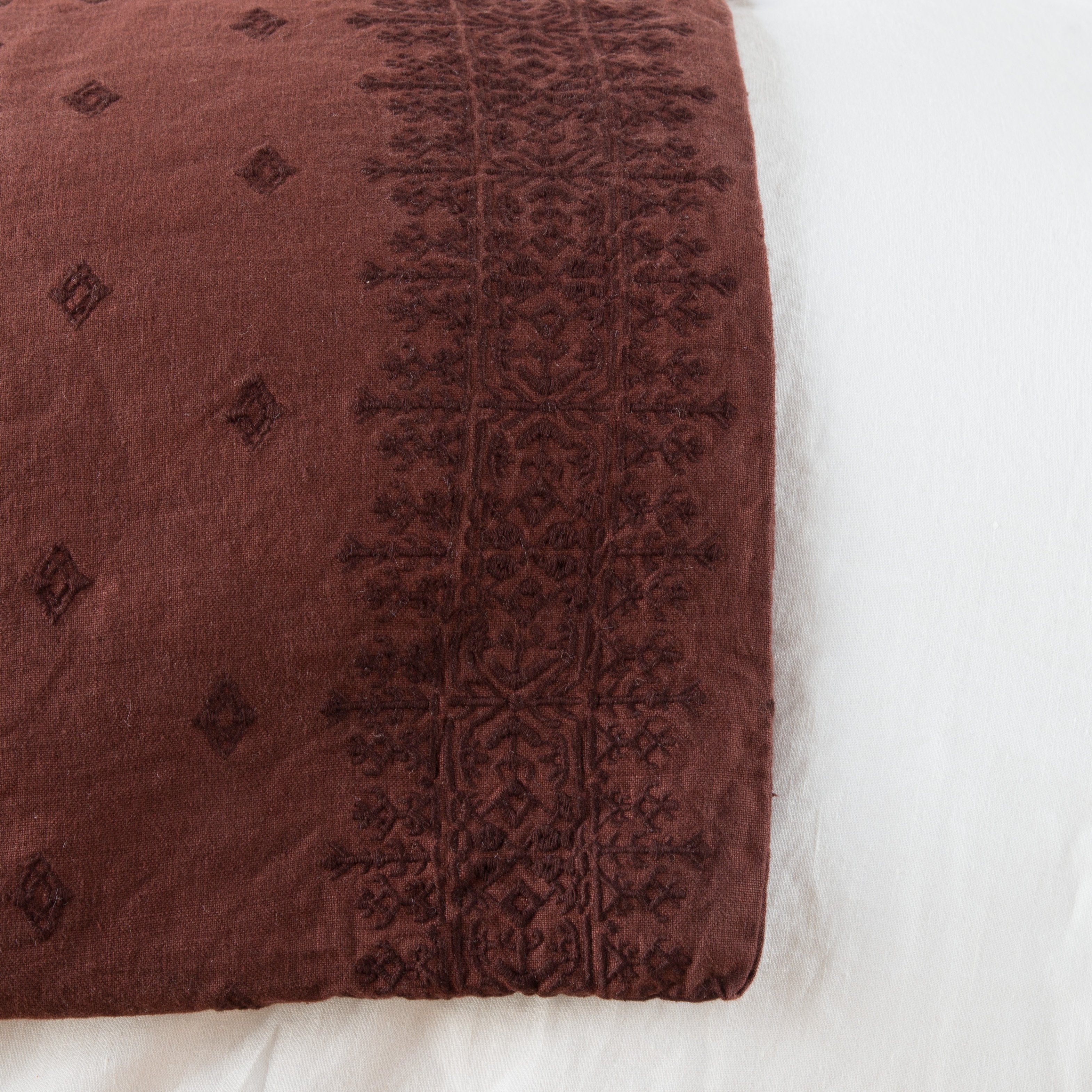 Mahogany: Close-up of corner against a white background, showcasing embroidery pattern detail - overhead view.
