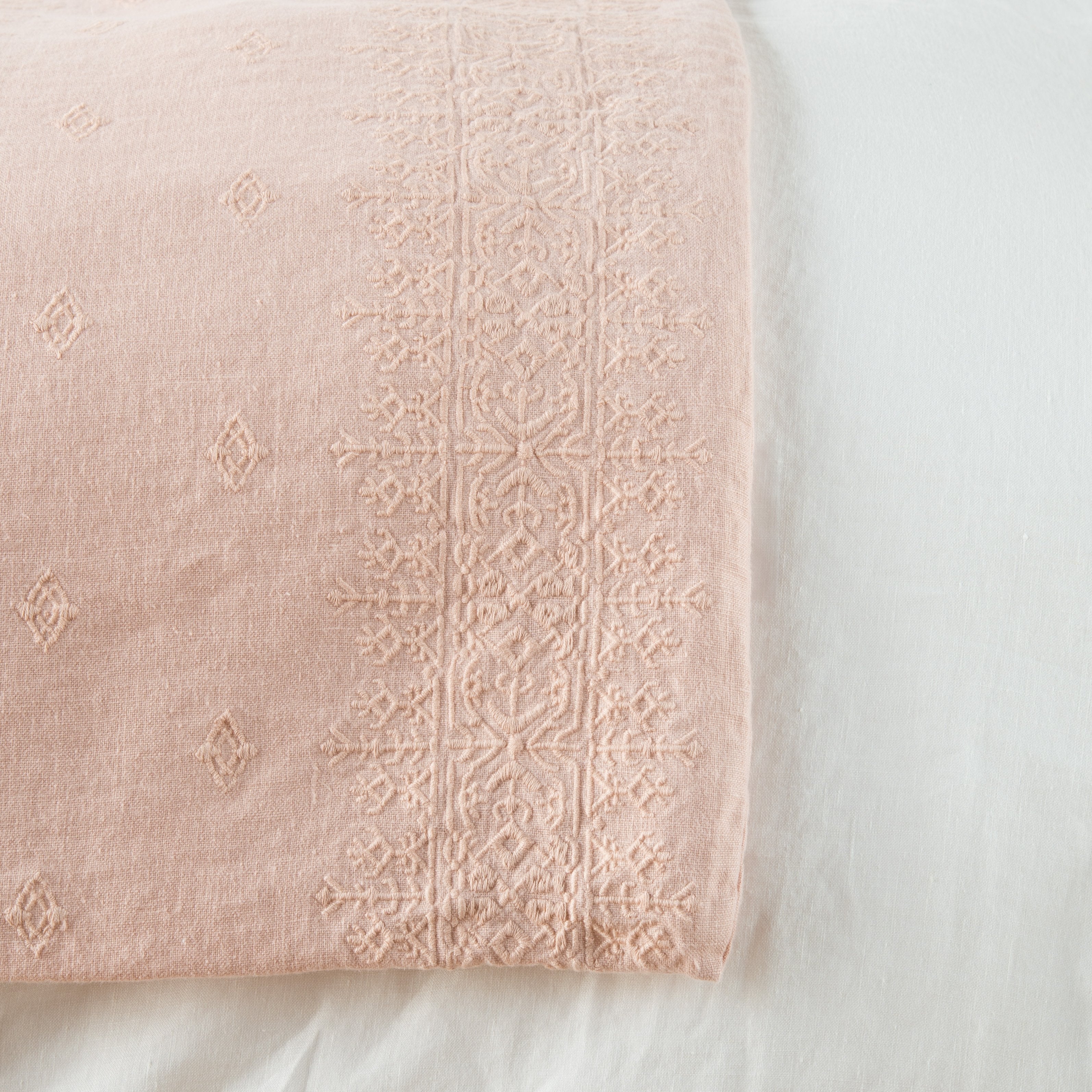 Rouge: Close-up of corner against a white background, showcasing embroidery pattern detail - overhead view.