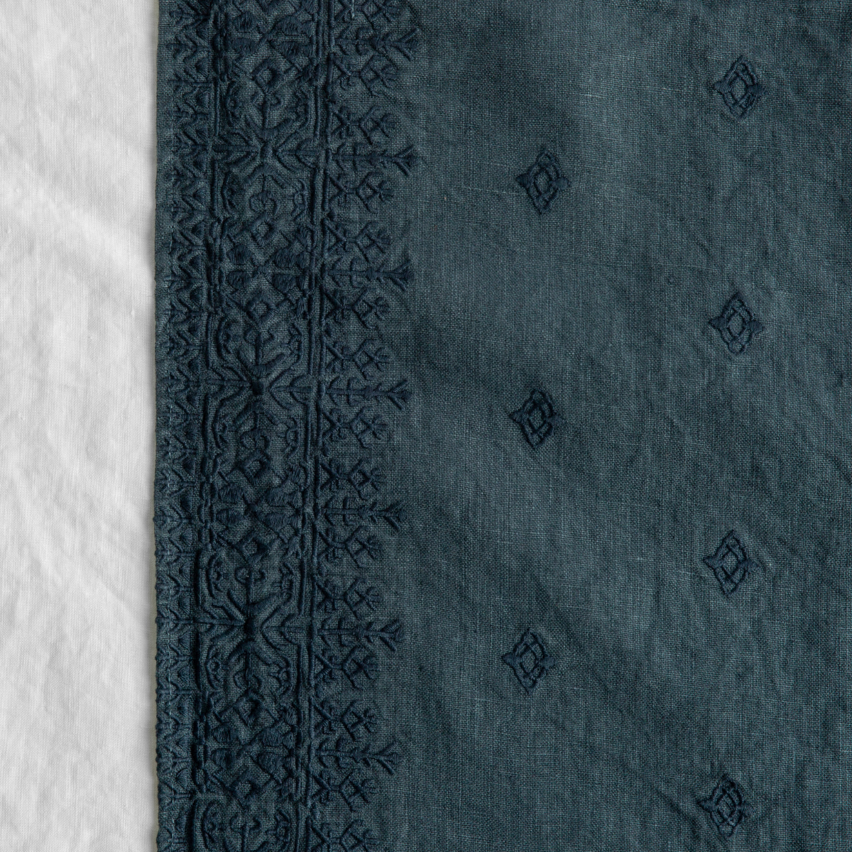 Midnight: A close up of Ines, midweight linen with cotton embroidery, in midnight, a rich indigo tone.